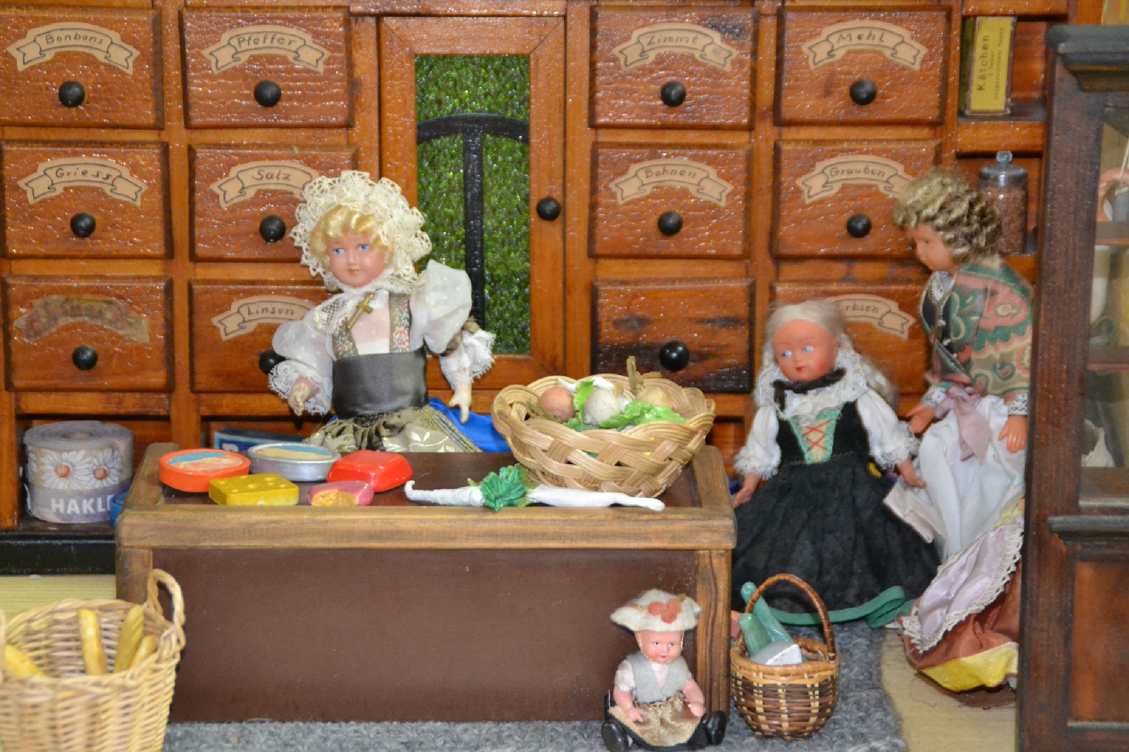 Detail b: Kaufladen, deutsch, um 1915, Holzgehäuse, Holzgalerie mit Tür und beschrifteten Schubläden (Salz, Bohnen, Mehl usw.), Holztheke, Hängeschränke, ...