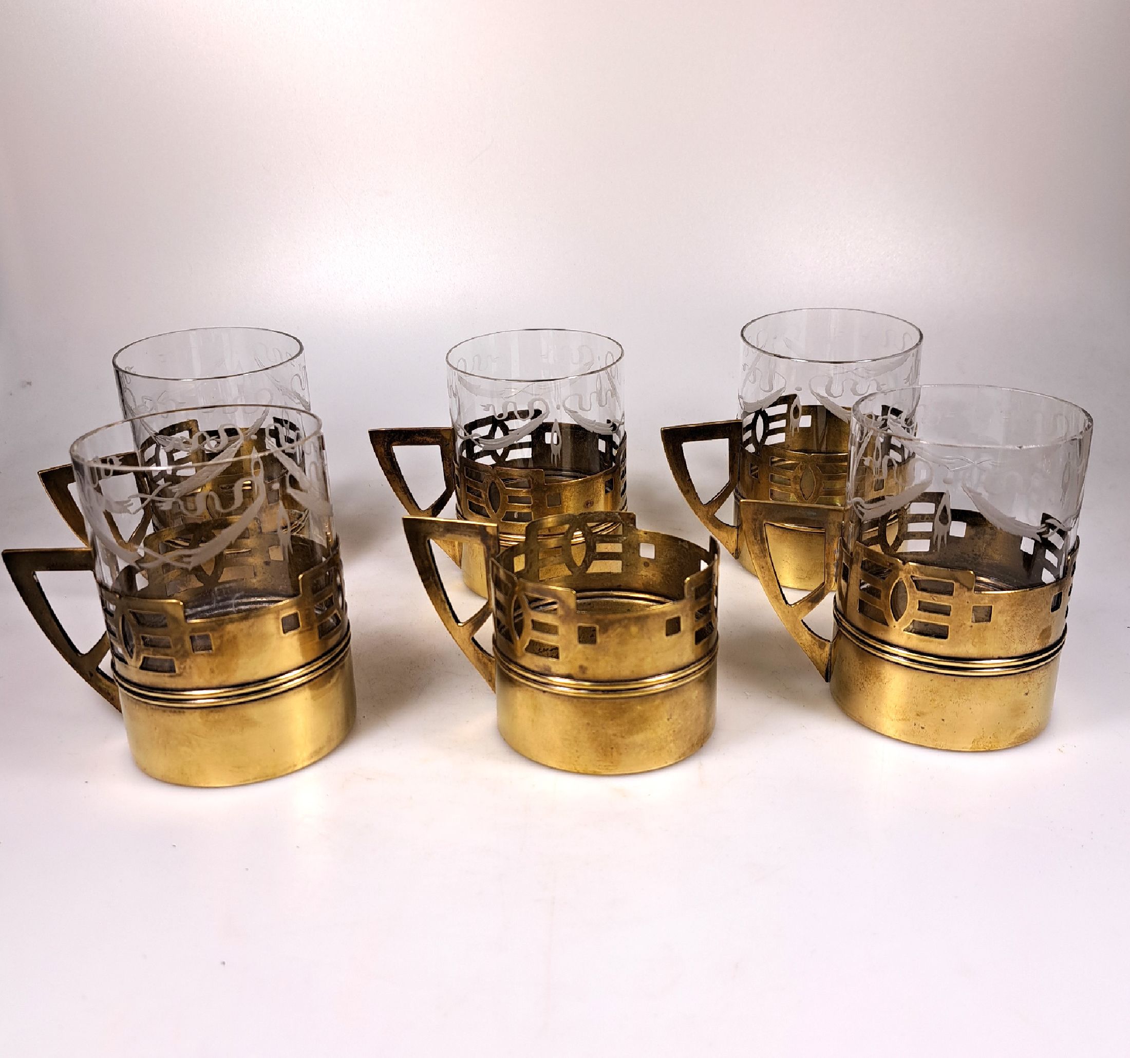 6 teiliges Heißgetränke-Service, Anfang 20.Jh., farbloses Glas geschliffen, Messingmonturmit geometrisierendem Dekor des Art Deco, ein Glaseinsatz ...