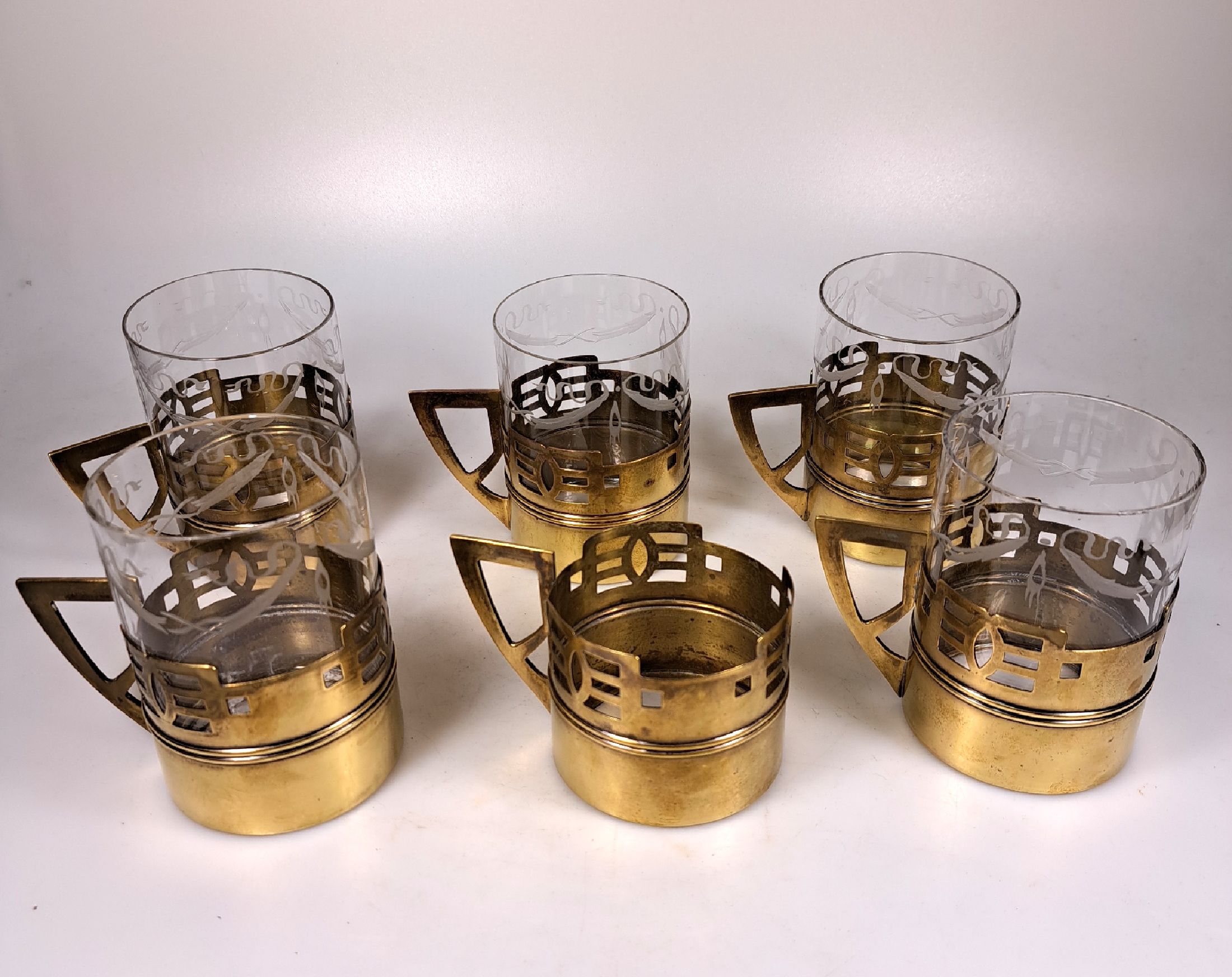 Detail a: 6 teiliges Heißgetränke-Service, Anfang 20.Jh., farbloses Glas geschliffen, Messingmonturmit geometrisierendem Dekor des Art Deco, ein Glaseinsatz ...