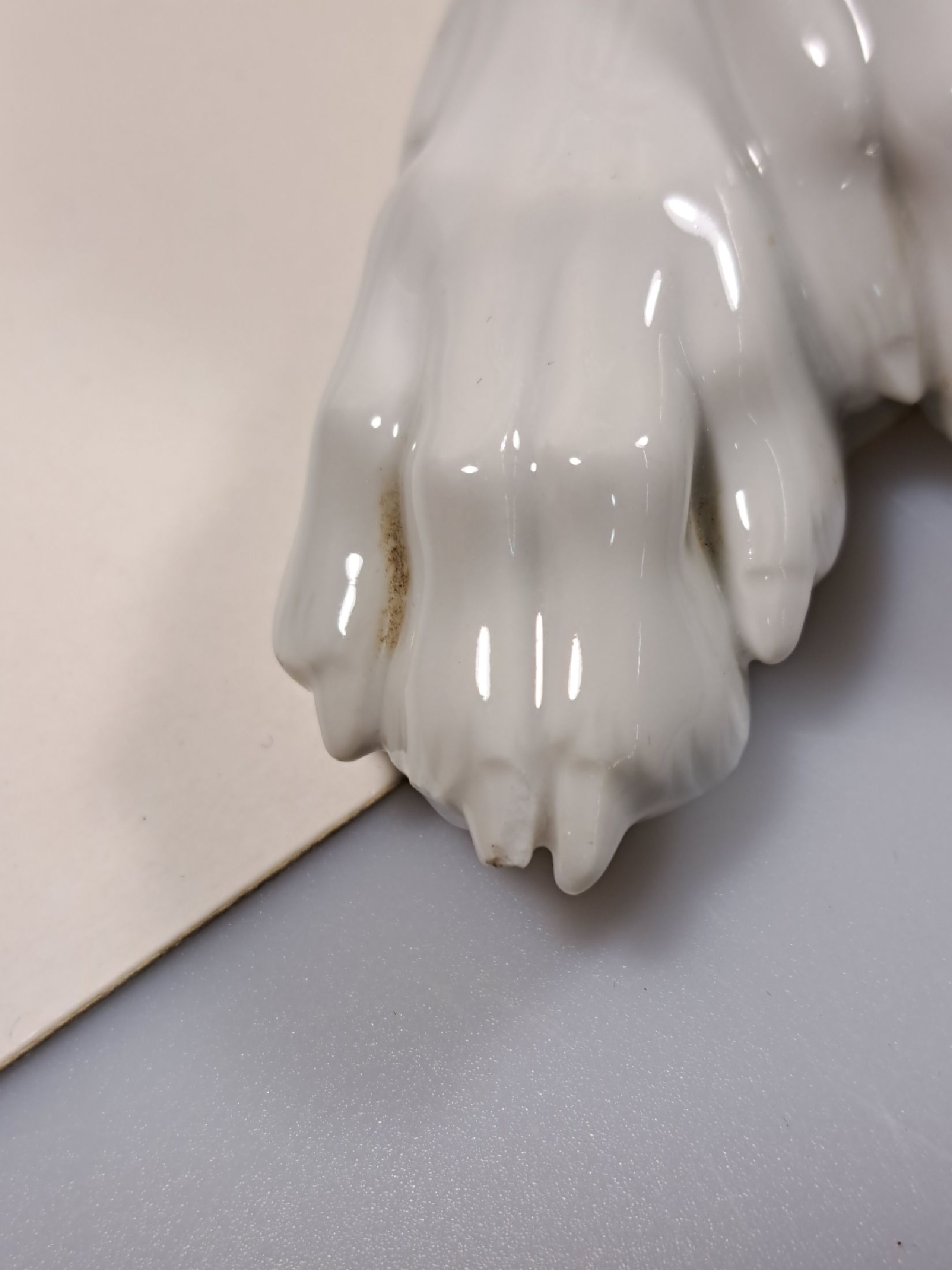 Detail h: Große Porzellanfigur, Allach, 1940er Jahre, liegender Schäferhund, weiß, Entwurf Theodor Kärner, sign., Blindmarke, Krallenspitze am Vorderlauf ...
