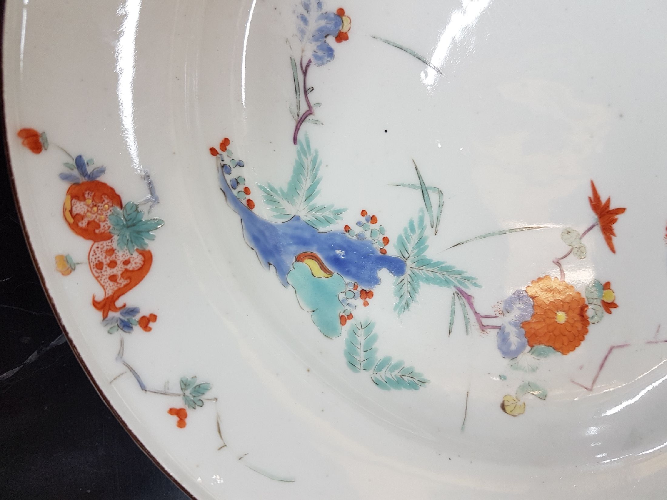 Detail b: Früher Teller, Meissen, um 1730, Kakiemondekor, Fels- und Vogel, feine polychrome Bemalung, brauner Rand, altersbedingt berieben, D.23 cm