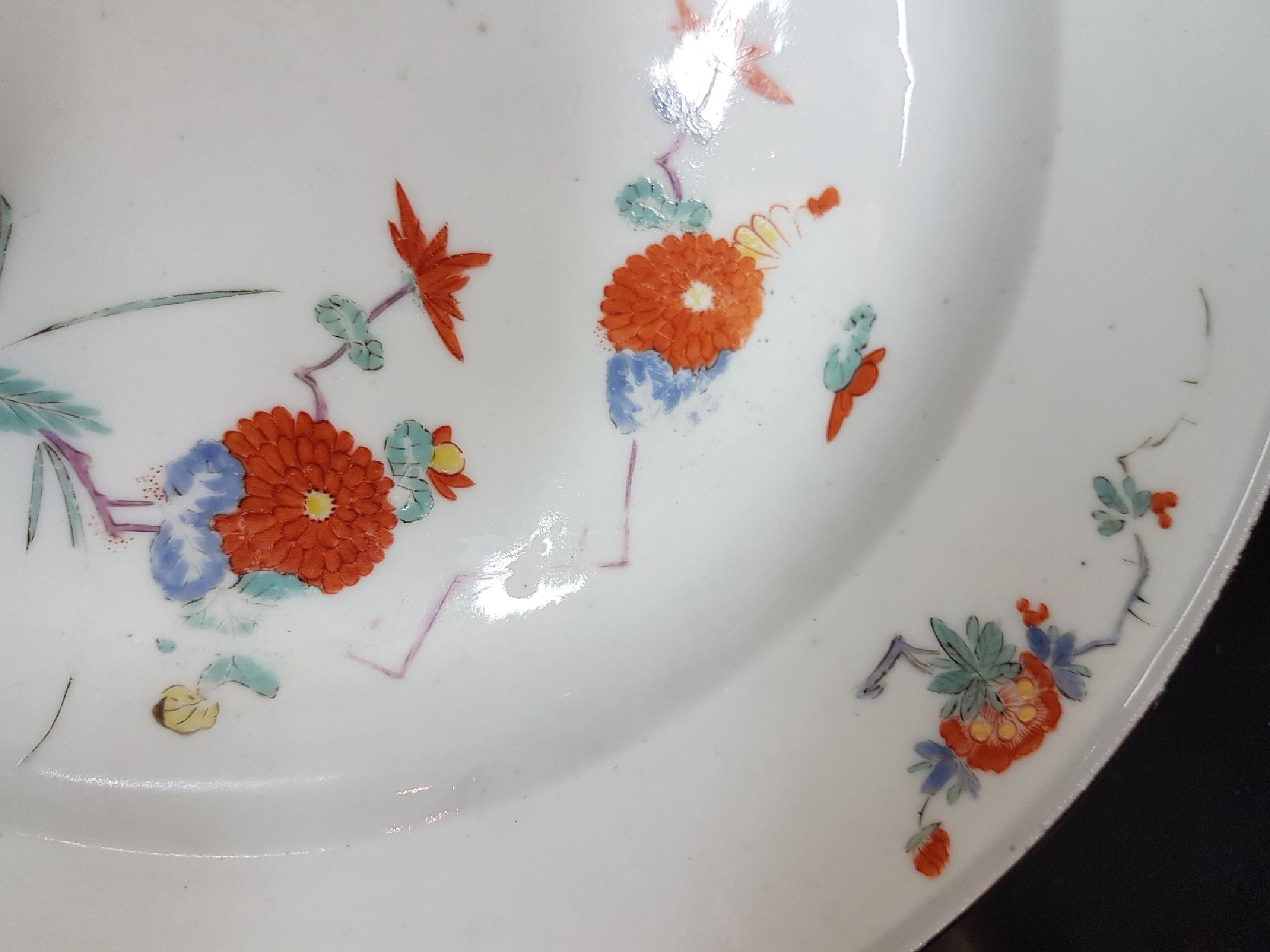 Detail c: Früher Teller, Meissen, um 1730, Kakiemondekor, Fels- und Vogel, feine polychrome Bemalung, brauner Rand, altersbedingt berieben, D.23 cm