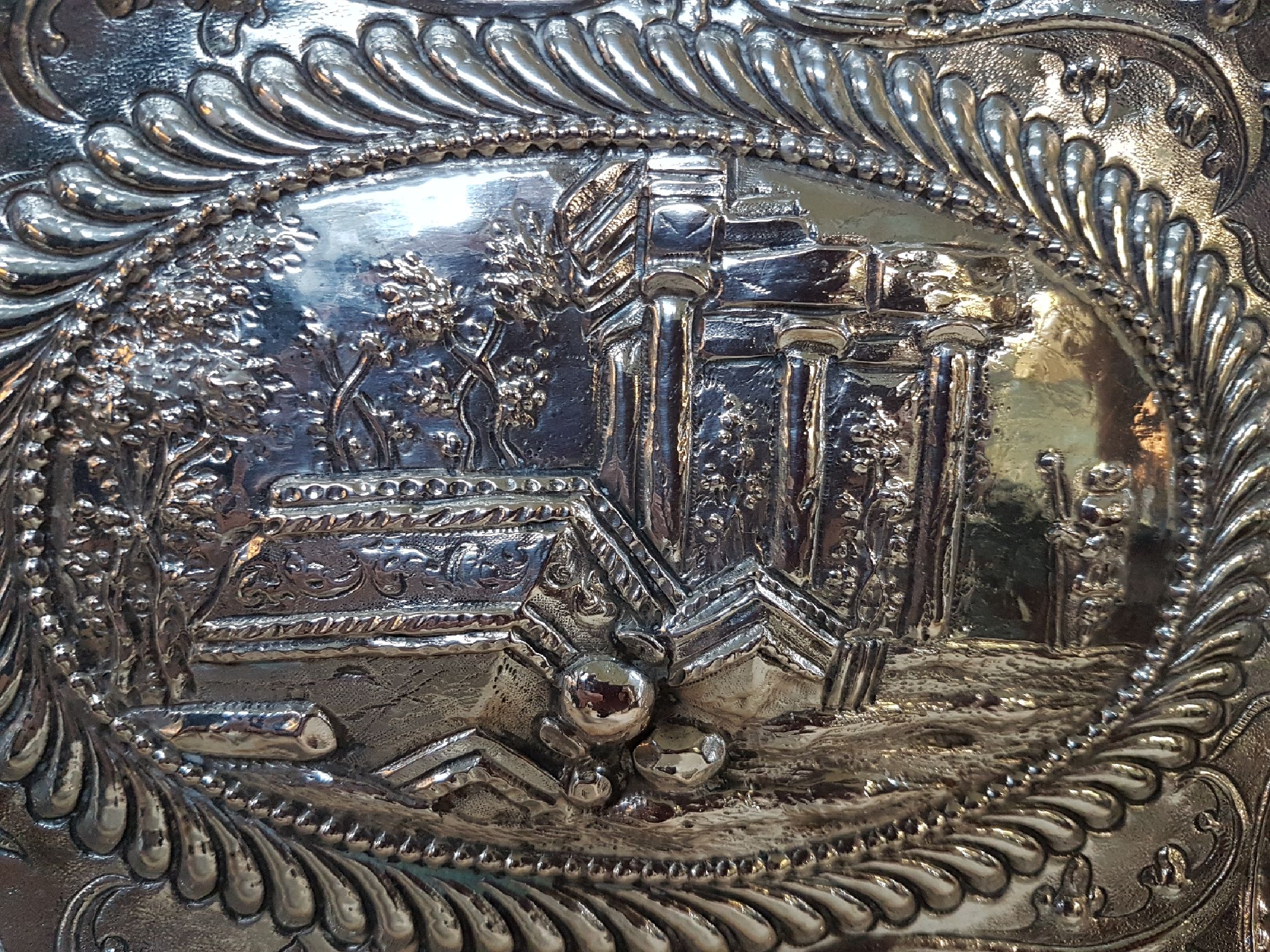 Detail c: Prunkplatte, Hamburg, 18. Jh., Silber, im Spiegel Ruinenlandschaft mit Schäfer, Fahne mit Bandelwerk und Blumen, Rand gekniffen, am Rand bez. ...