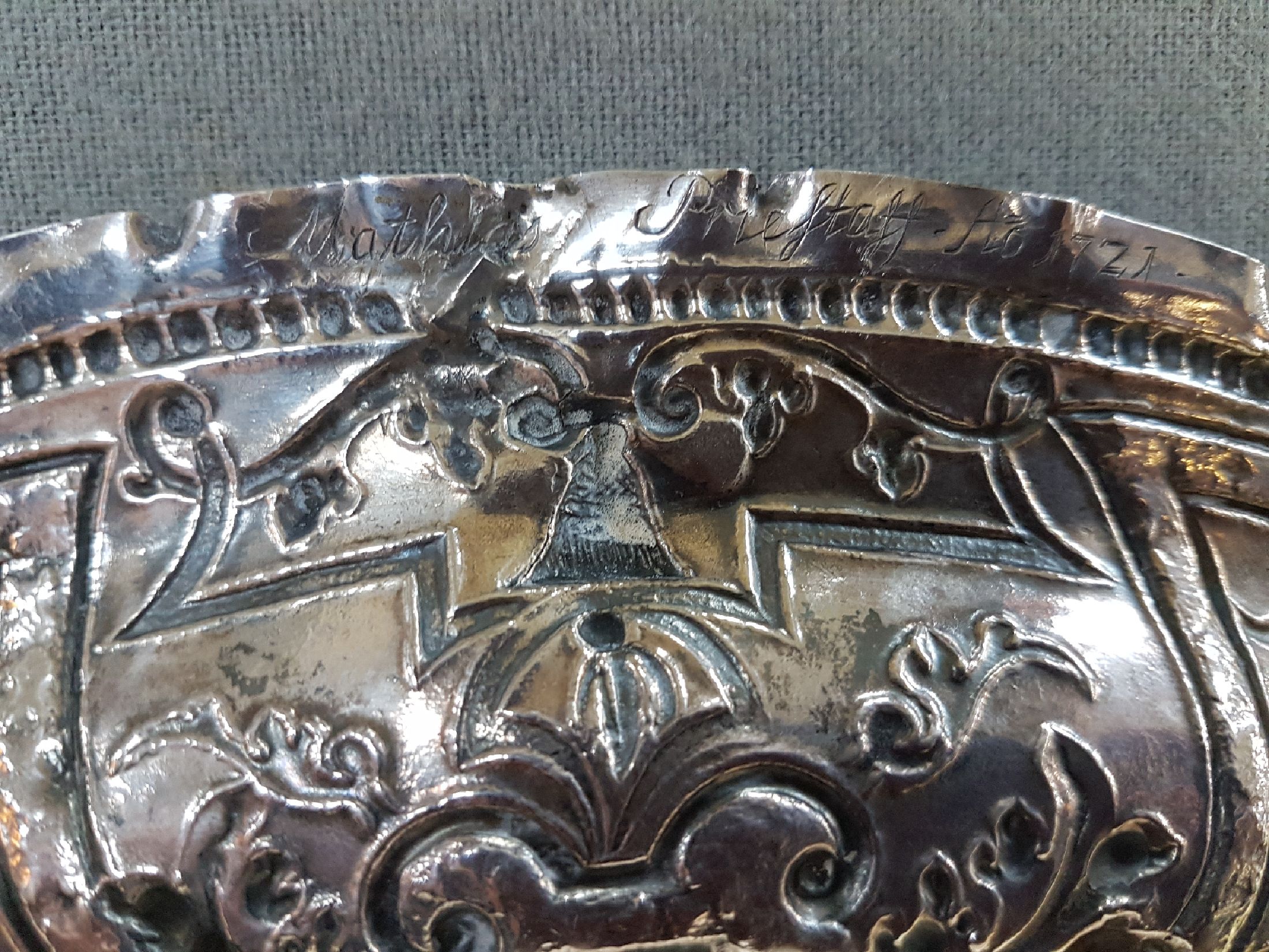 Detail h: Prunkplatte, Hamburg, 18. Jh., Silber, im Spiegel Ruinenlandschaft mit Schäfer, Fahne mit Bandelwerk und Blumen, Rand gekniffen, am Rand bez. ...
