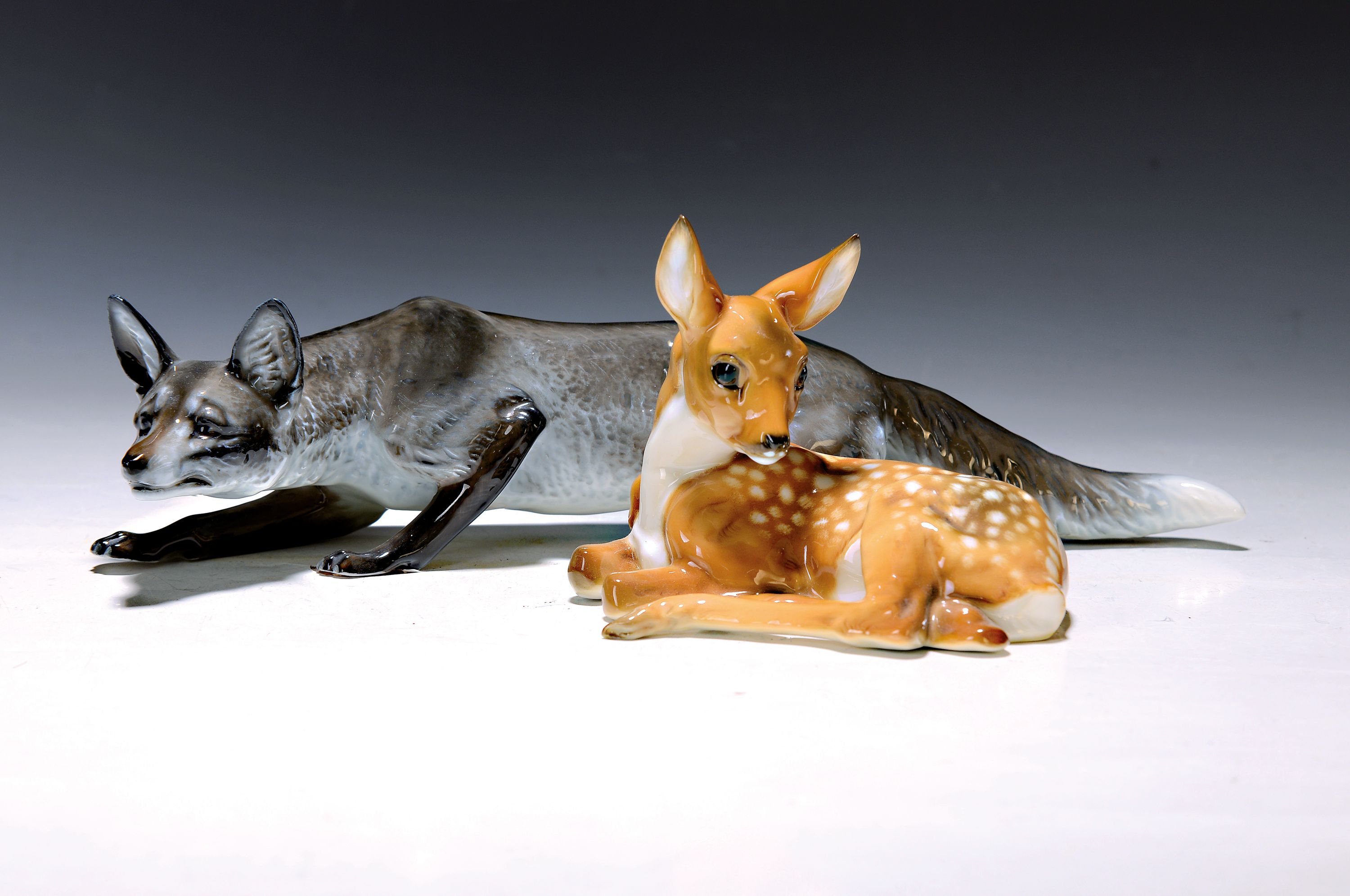 Zwei Porzellanfiguren, schleichender Fuchs, Rosenthal und liegendes Kitz, Hutschenreuther, 20.Jh., Porzellan, naturalistisch bemalt, Fuchs Entw. ...