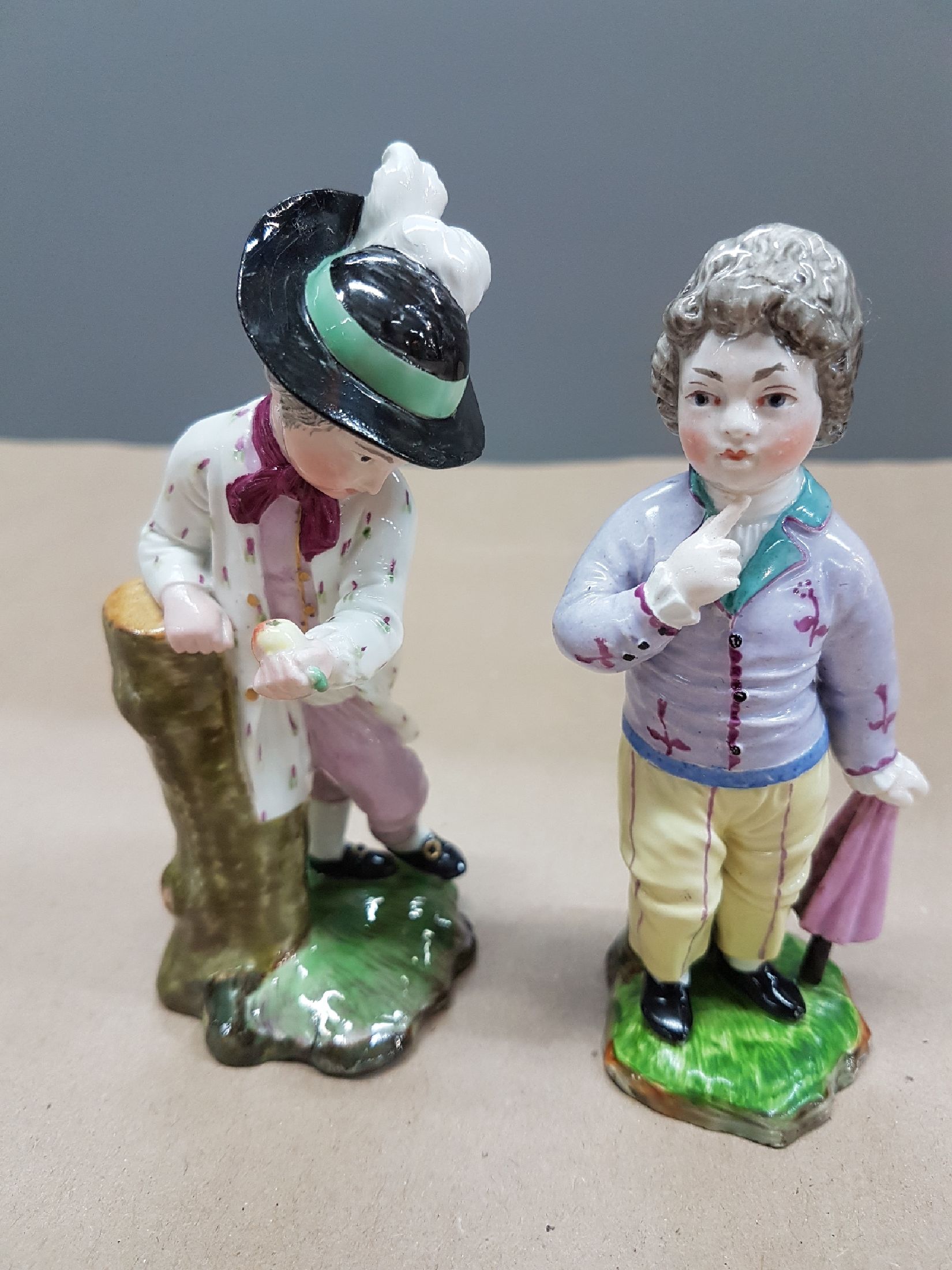 Detail a: Zwei Figuren, Entwurf J.P. Melchior, Höchst, Knabe mit Birne, l. fachgerecht rest., H. ca. 12 cm und Damm, Knabe mit Regenschirm, Ritzmarke 214, ...