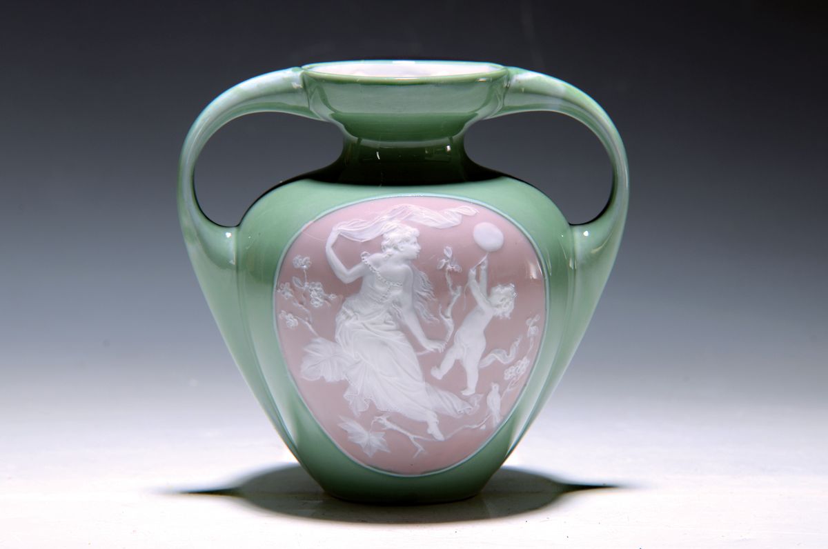 Doppelhenkelvase, Frankreich, um 1900, Pate-sur-pate, grüner Fond, in grossem Medaillon Mädchendarstellung in blühendem Geäst, daneben Putto mit ...