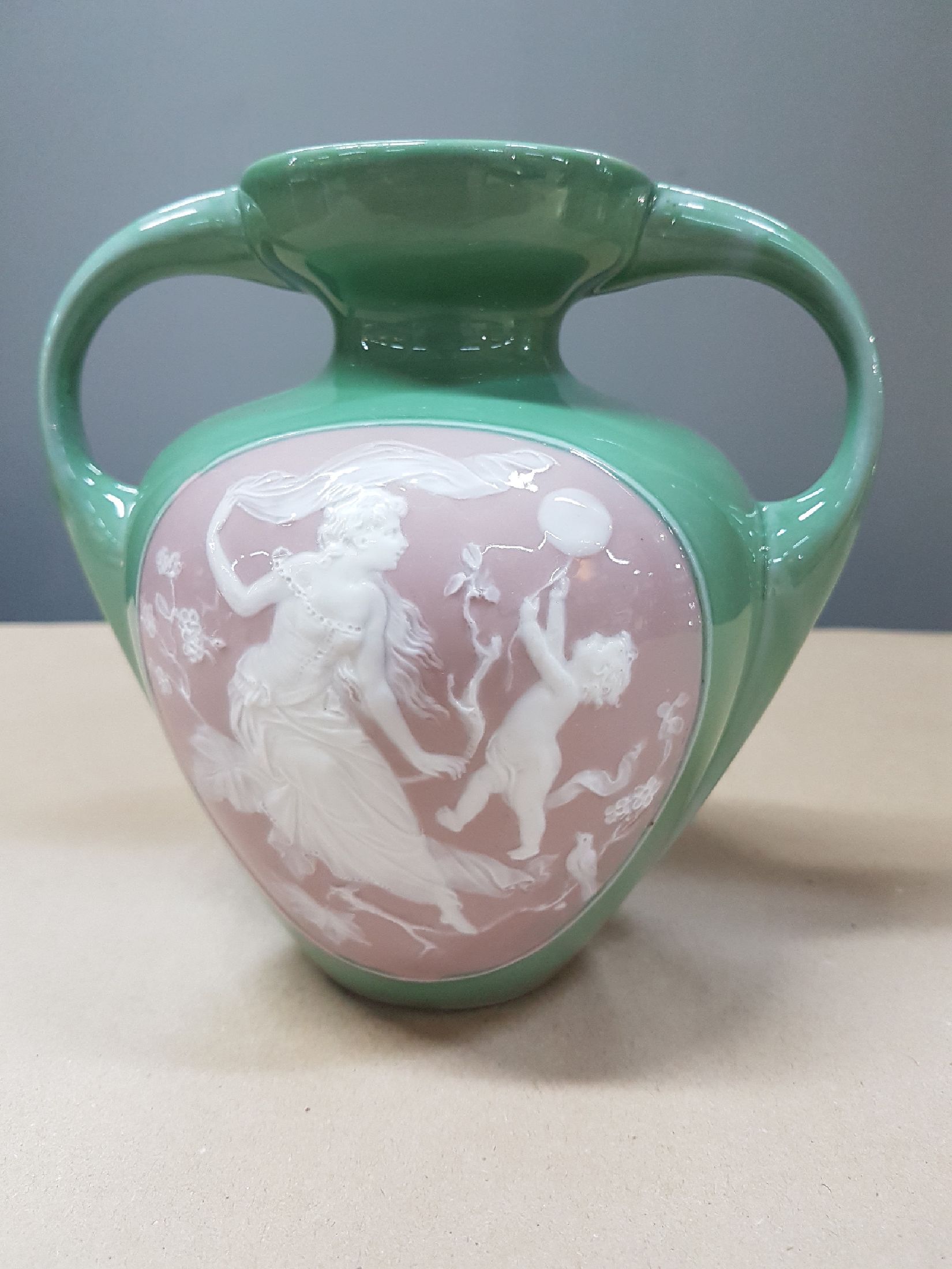 Detail a: Doppelhenkelvase, Frankreich, um 1900, Pate-sur-pate, grüner Fond, in grossem Medaillon Mädchendarstellung in blühendem Geäst, daneben Putto mit ...