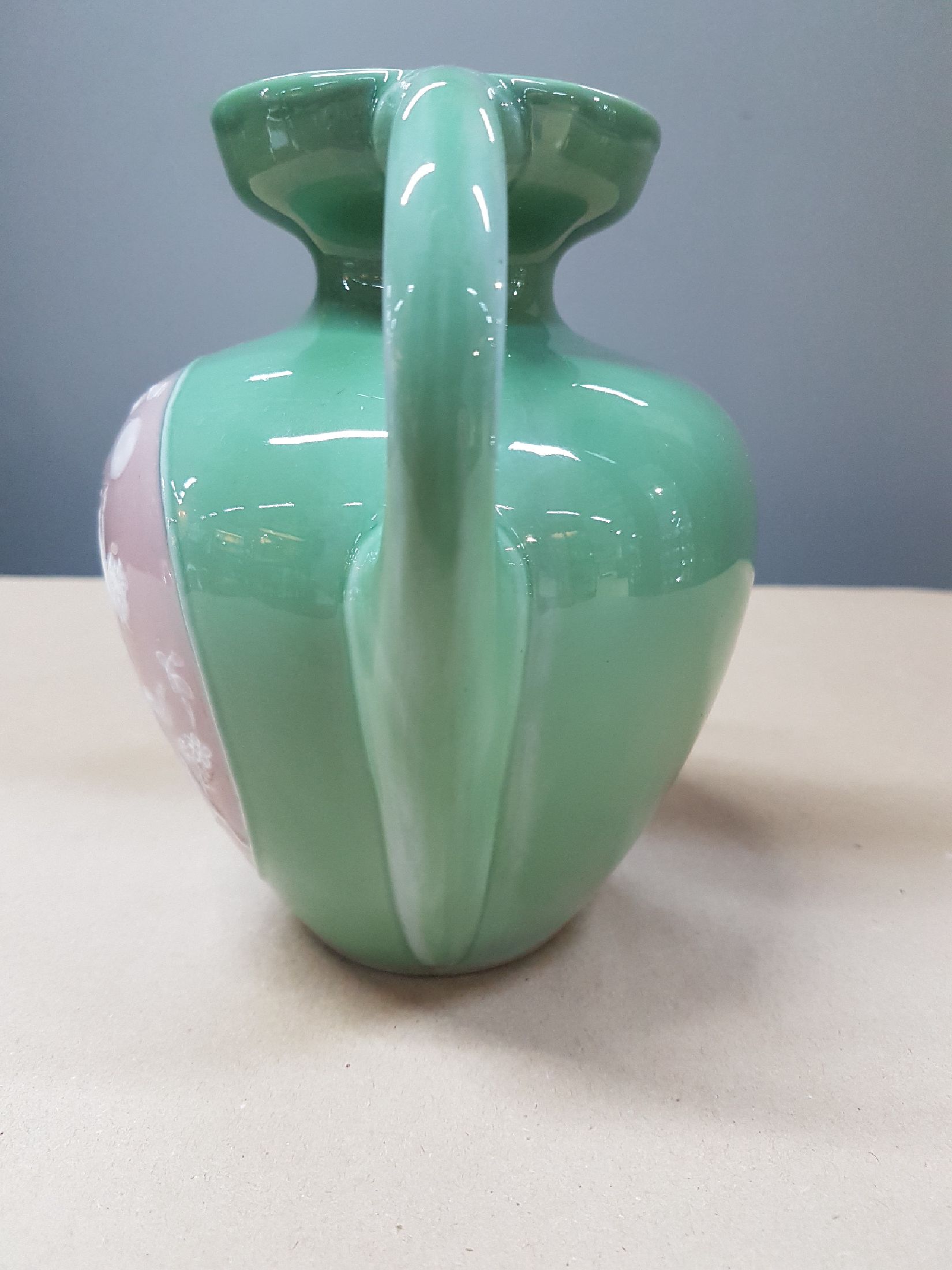 Detail d: Doppelhenkelvase, Frankreich, um 1900, Pate-sur-pate, grüner Fond, in grossem Medaillon Mädchendarstellung in blühendem Geäst, daneben Putto mit ...