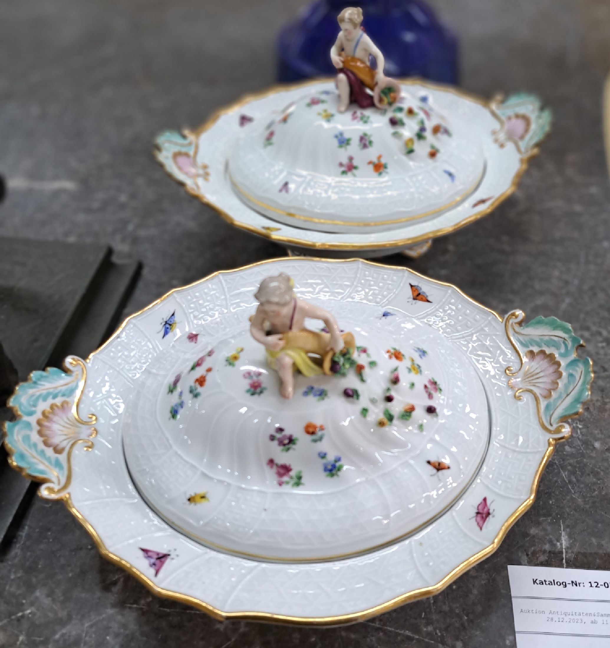Detail a: Zwei Deckelschalen, Meissen, um 1880-90, 1. und 2. Wahl, Neubrandensteinrelief, Griffe altrosa und türkis gefaßt, Figurenbekrönung mit Füllhorn, ...
