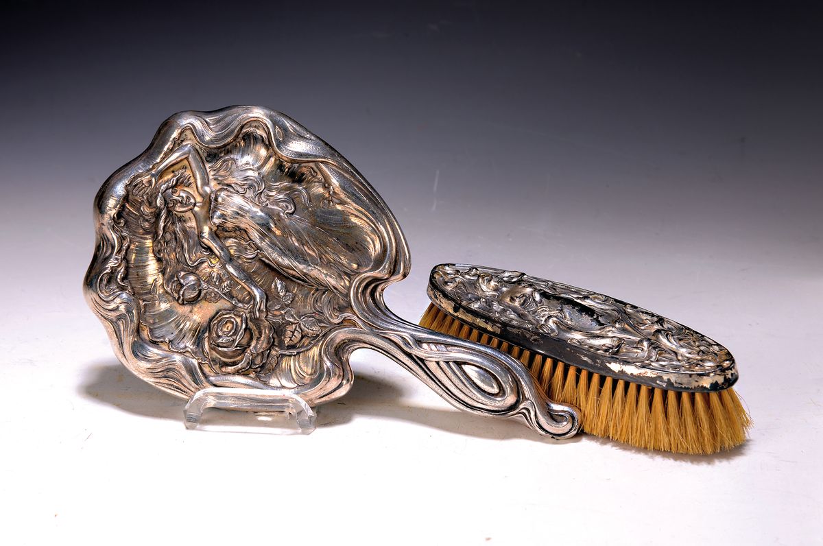Handspiegel und Bürste, Frankreich, um 1900, Jugendstil, Metall versilbert, reich geprägt mit Frauenfigur und Blumen, berieben, L. ca. 25/17cm