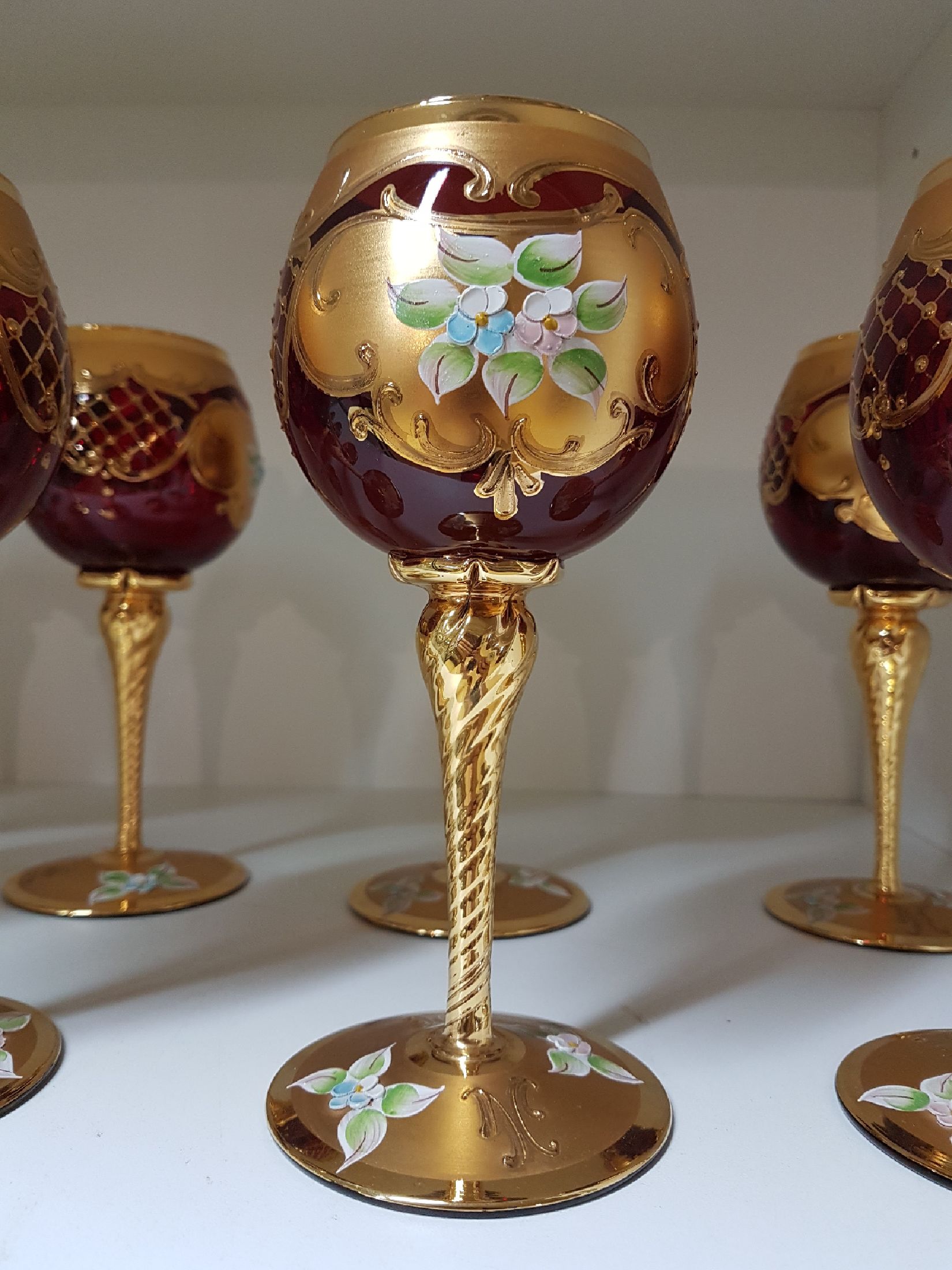 Detail b: 12 Weingläser, Murano Italien, 1970er Jahre, rubinrotes Glas, reich vergoldet und mit bunter floraler Emailmalerei, H. je ca. 19.5cm