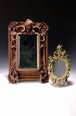 Image 26706245 - Two mirrors, 18th century and around 1900: small baroque frame, carved lime wood, with rose and flower decoration, mirror glass supplemented and partly coated, height approx. 30 cm, plus a wall mirror around 1900, wooden frame with partly fully sculptural carvings by Rocailles, flowers and angel head, cut mirror, approx. 41 x 28 cm, both with traces of age and usage