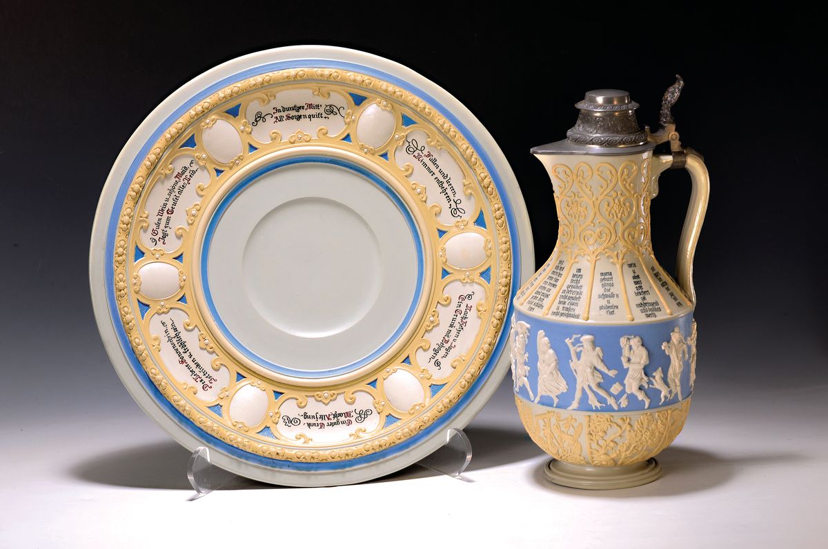 Weinkanne mit Unterteller, Villeroy & Boch Mettlach, um 1900, Feinsteinzeug, partiell blau glasiert, aufgelegter Fries von tanzenden Menschen, ...