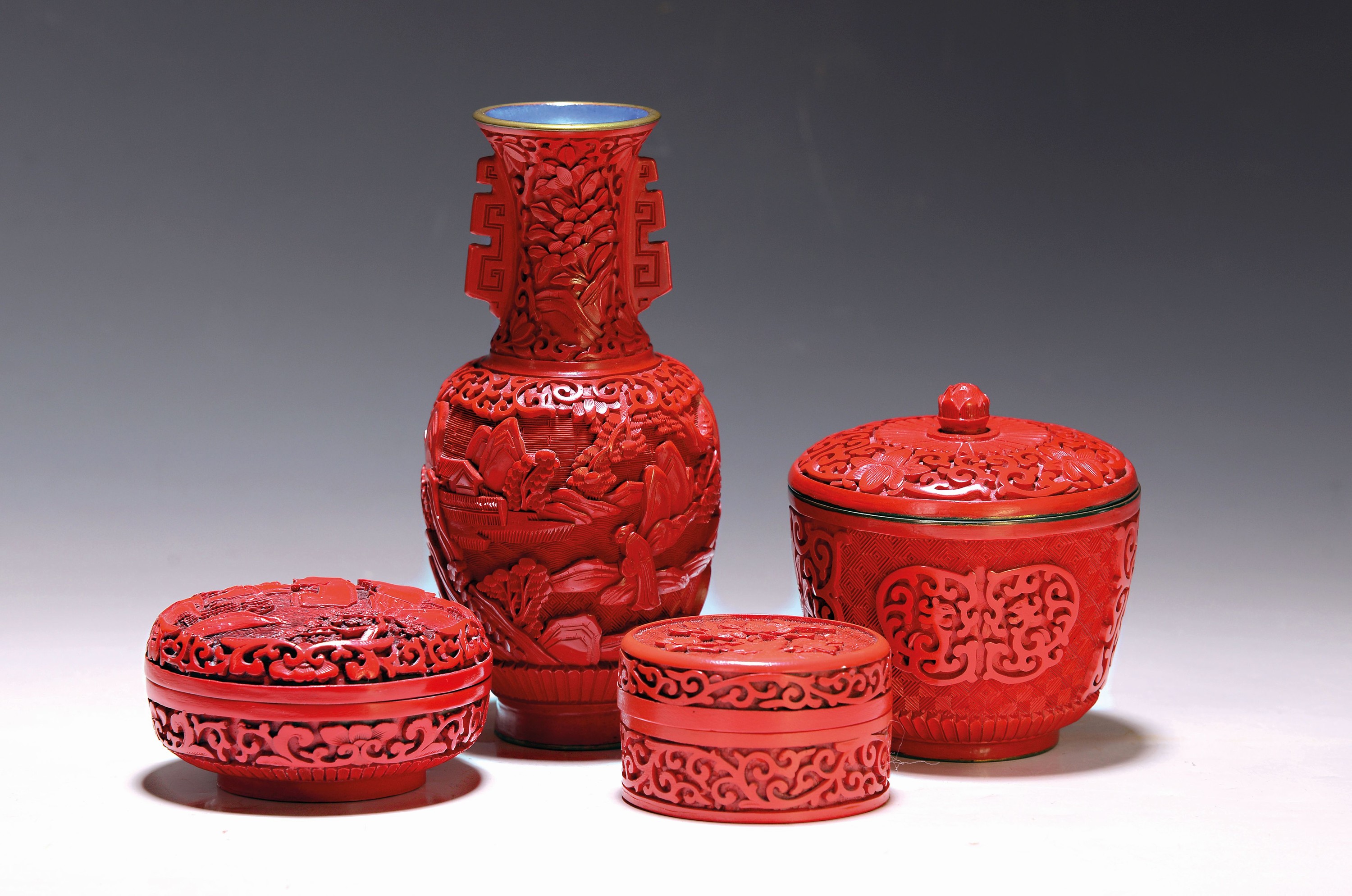 4 Rotlack-Gefäße, China, 2. Hälfte 20. Jh., geschnitzt, eine Vase Landschaftsmotiv und Personen, H. ca. 17.5 cm, Deckeldose stil. Landschaft, D. 9 ...