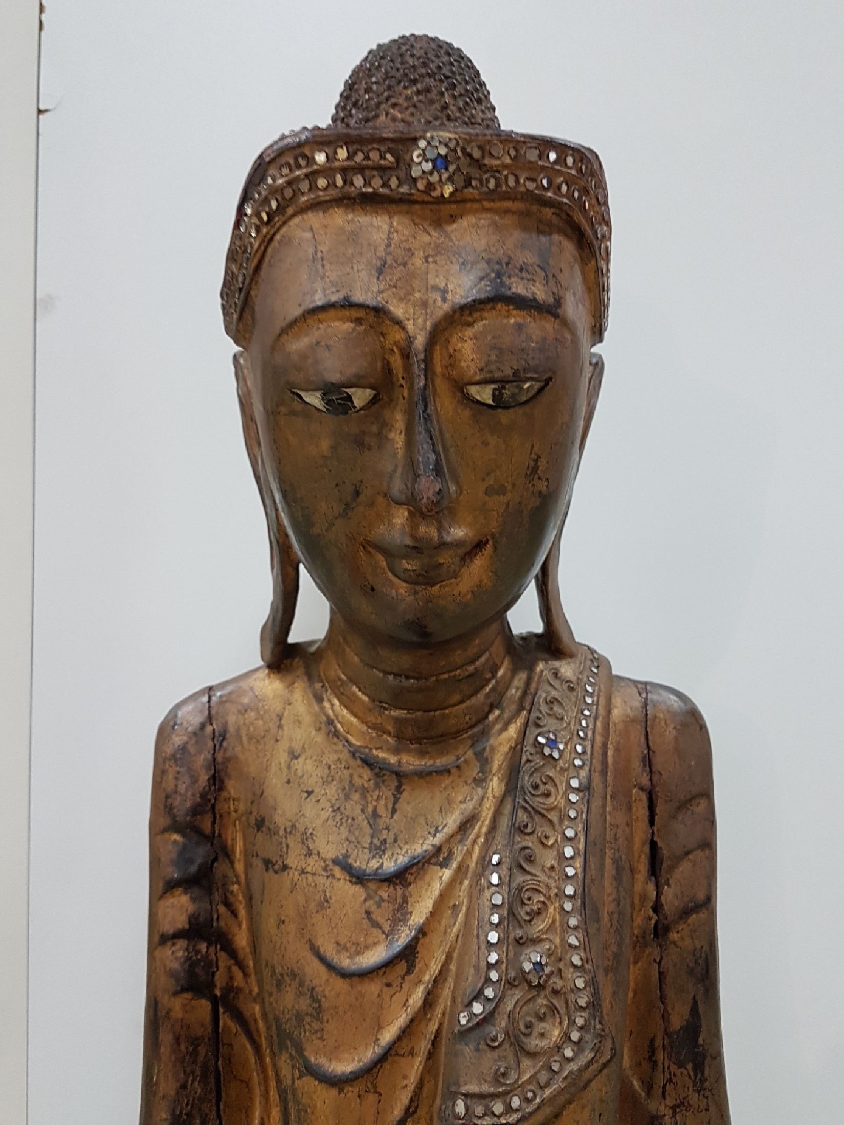 Detail a: Großer stehender Buddha, Burma, Anfang 20. Jh., Holz geschnitzt, mit Spiegeleinsätzen, gefaßt, leicht beschädigt, H. ca. 103 cm
