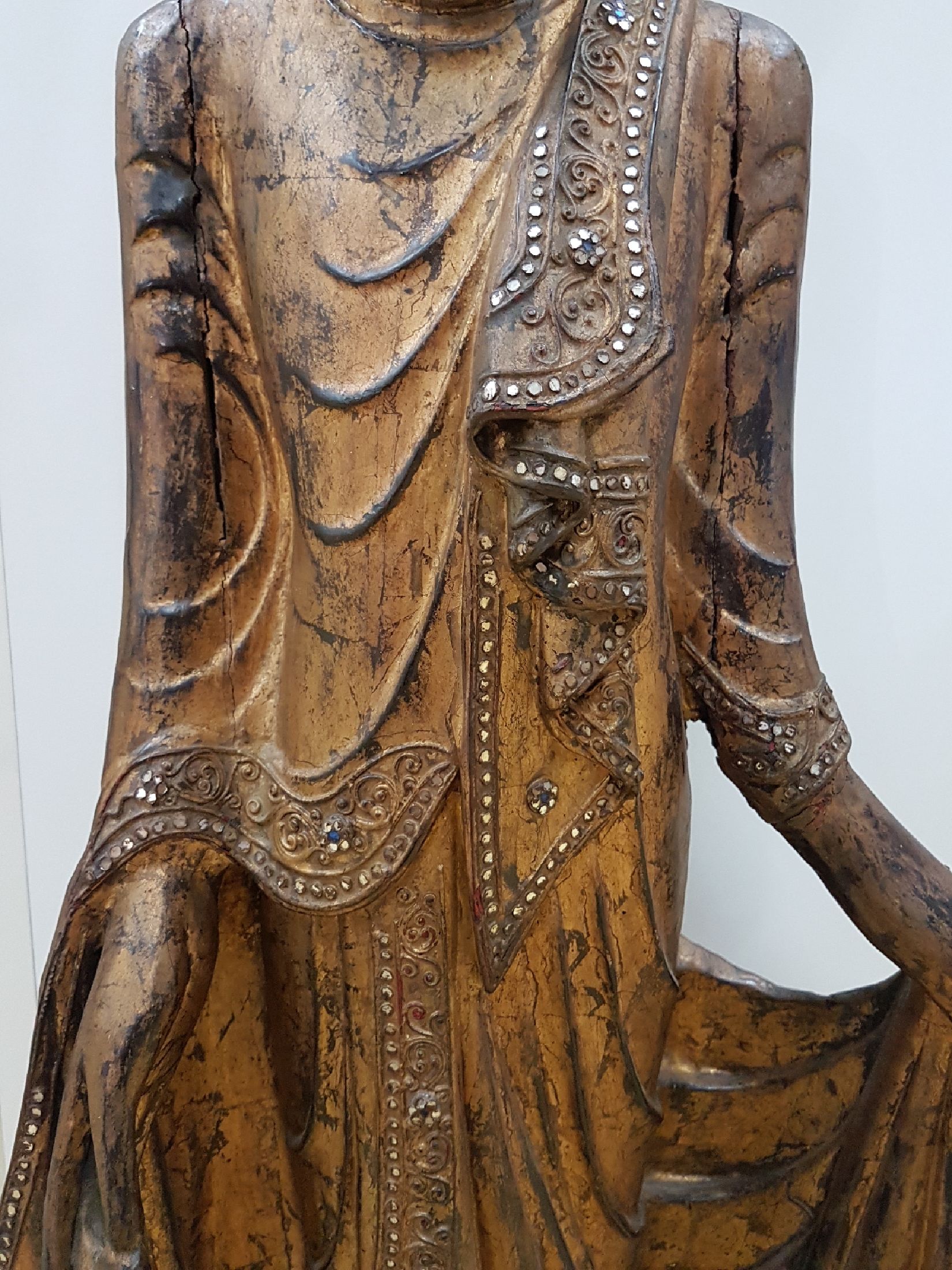 Detail b: Großer stehender Buddha, Burma, Anfang 20. Jh., Holz geschnitzt, mit Spiegeleinsätzen, gefaßt, leicht beschädigt, H. ca. 103 cm