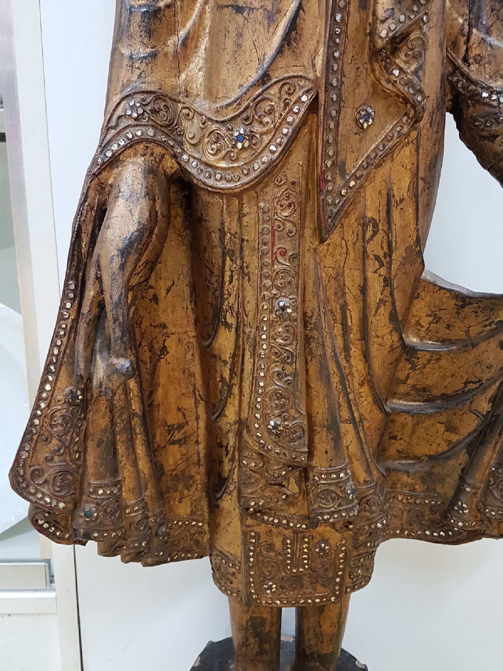 Detail c: Großer stehender Buddha, Burma, Anfang 20. Jh., Holz geschnitzt, mit Spiegeleinsätzen, gefaßt, leicht beschädigt, H. ca. 103 cm