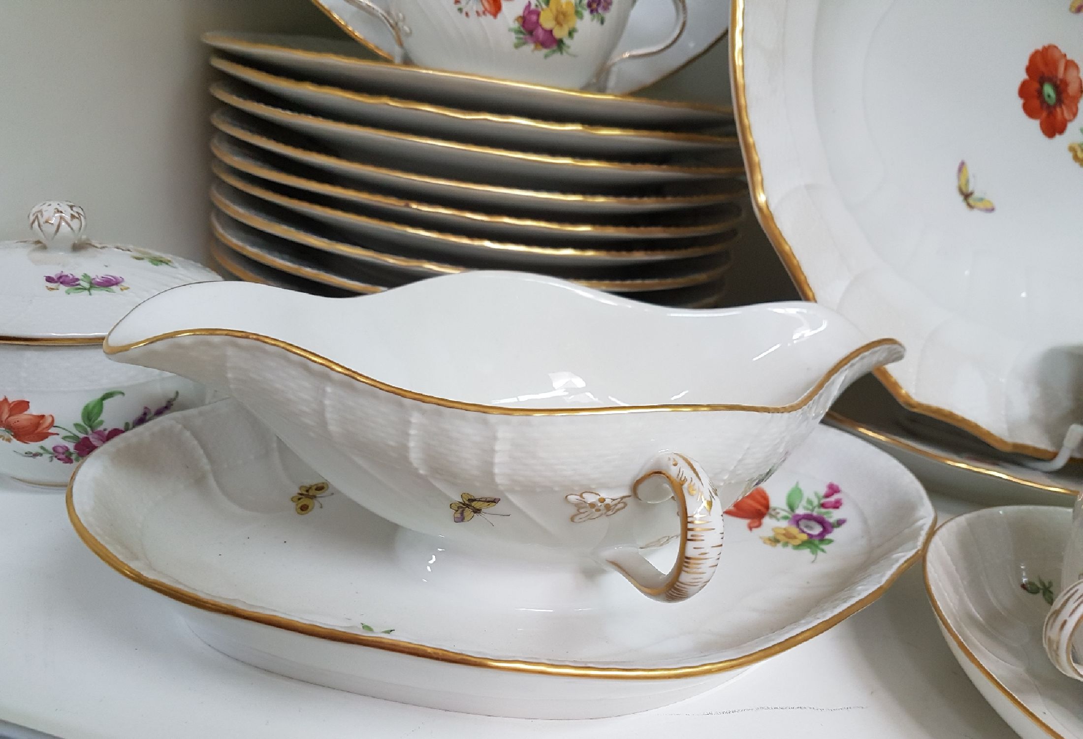 Detail b: Tafelservice/Speiseservice für 12 Personen, KPM Neuosier, 20. Jh., Blumenmalerei und Schmetterlingen bemalt, Goldränder, 12 Menueteller D. 26 cm, ...