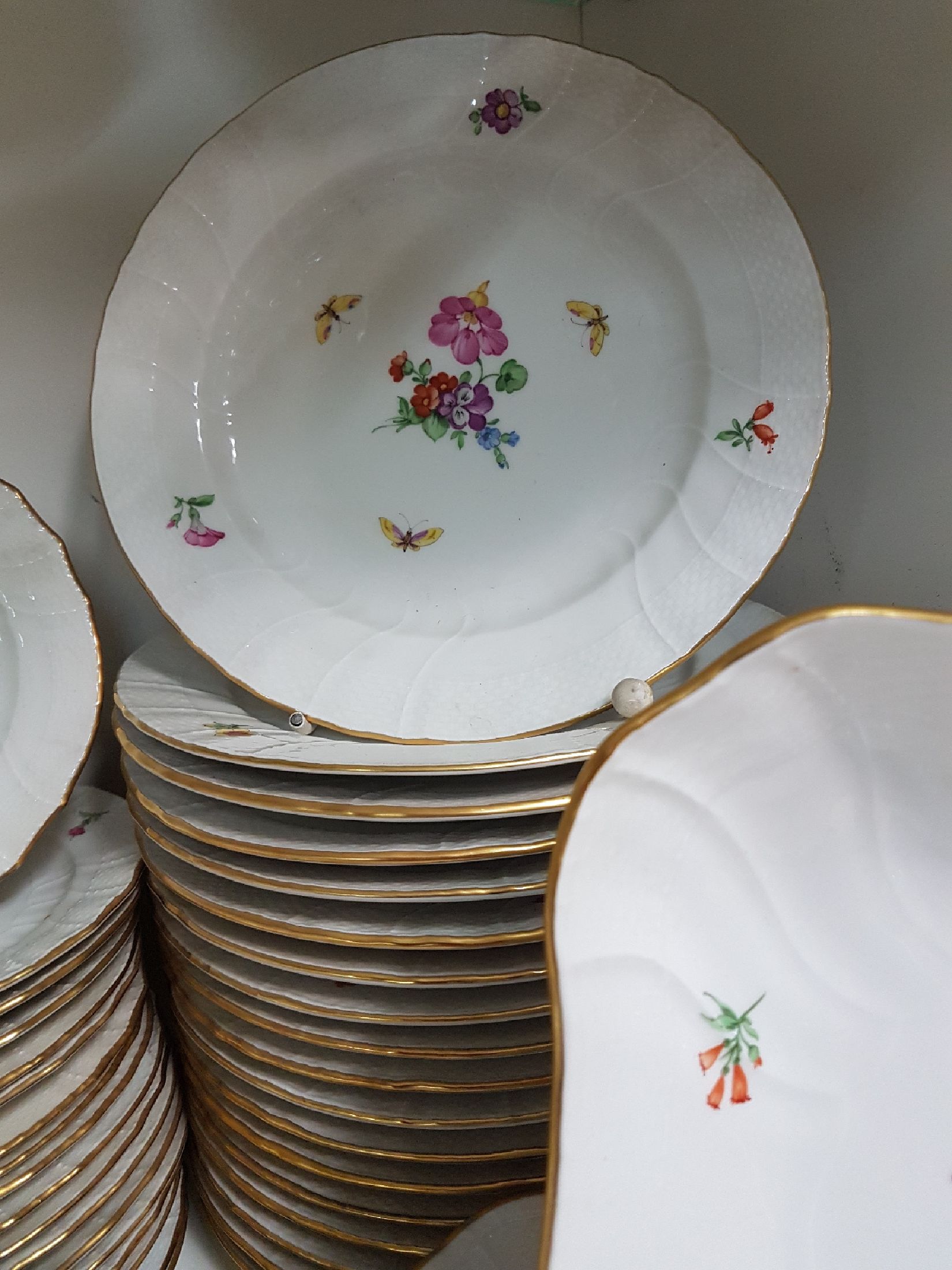 Detail d: Tafelservice/Speiseservice für 12 Personen, KPM Neuosier, 20. Jh., Blumenmalerei und Schmetterlingen bemalt, Goldränder, 12 Menueteller D. 26 cm, ...