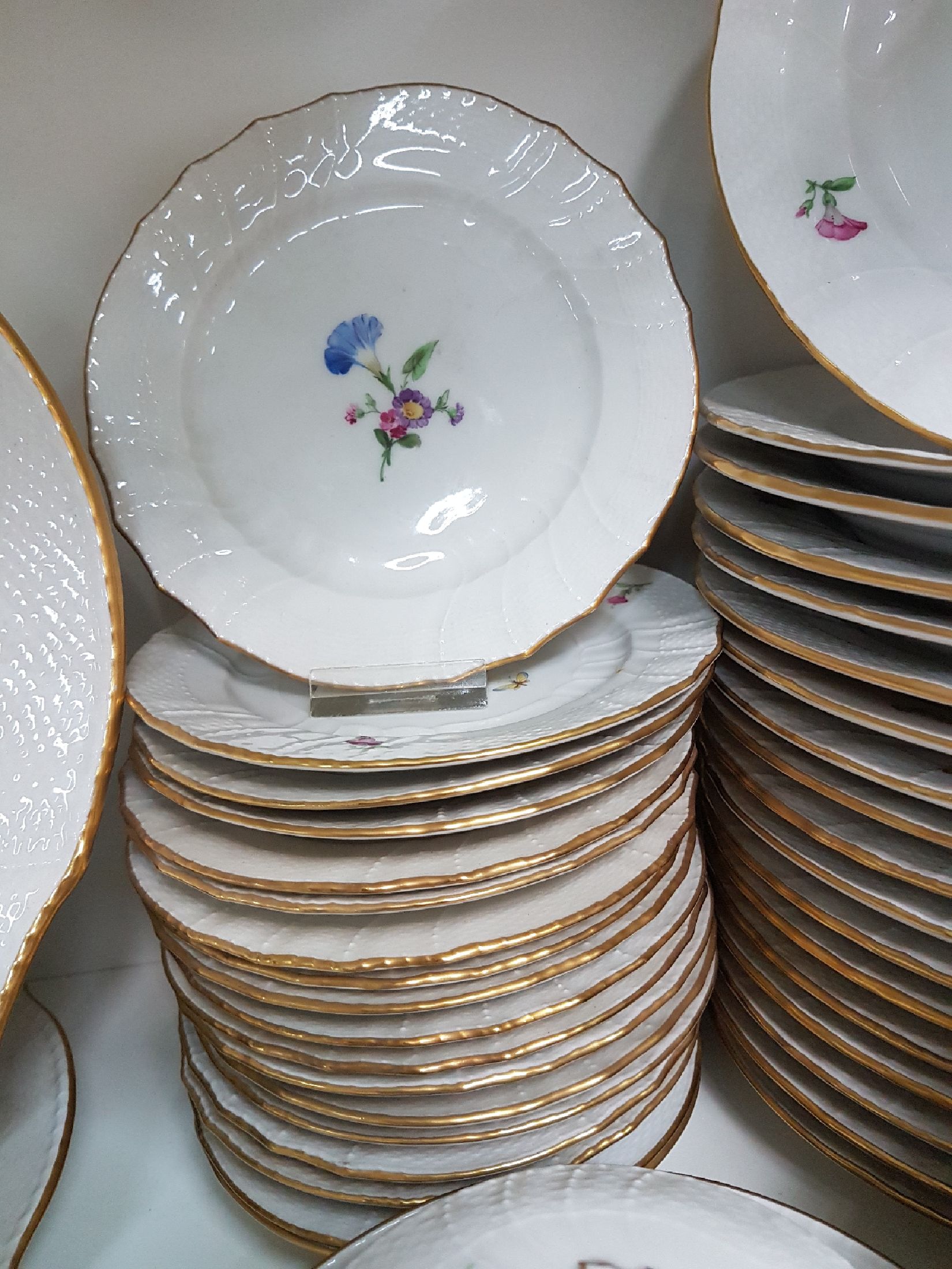 Detail e: Tafelservice/Speiseservice für 12 Personen, KPM Neuosier, 20. Jh., Blumenmalerei und Schmetterlingen bemalt, Goldränder, 12 Menueteller D. 26 cm, ...