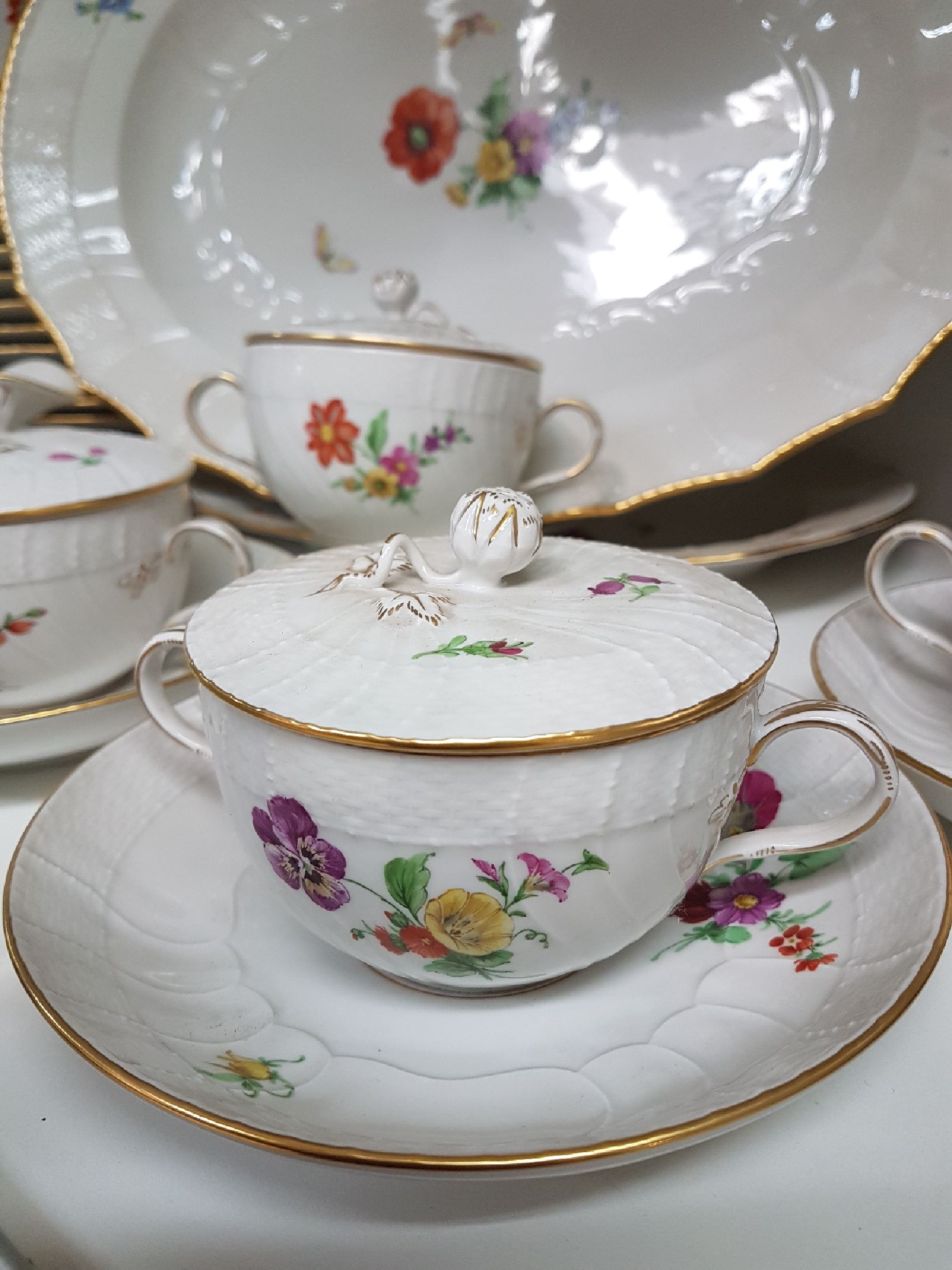 Detail g: Tafelservice/Speiseservice für 12 Personen, KPM Neuosier, 20. Jh., Blumenmalerei und Schmetterlingen bemalt, Goldränder, 12 Menueteller D. 26 cm, ...