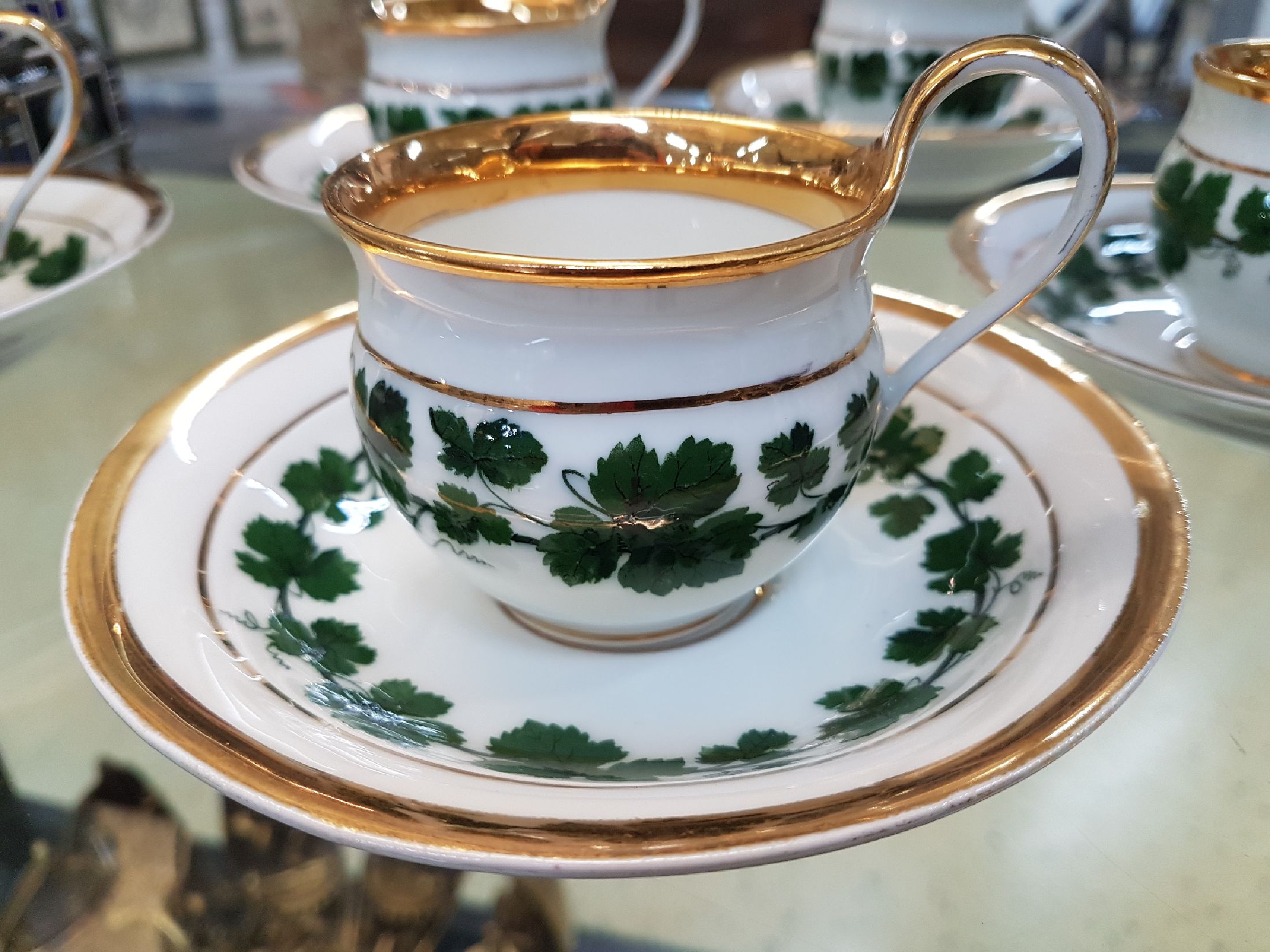 Detail c: 6 kleine Tassen mit Untertassen, Meissen, um 1890-1900, Porzellan, Dekor grüner Weinkranz, breite Glanzgoldränder, leicht berieben, eine Untertasse ...