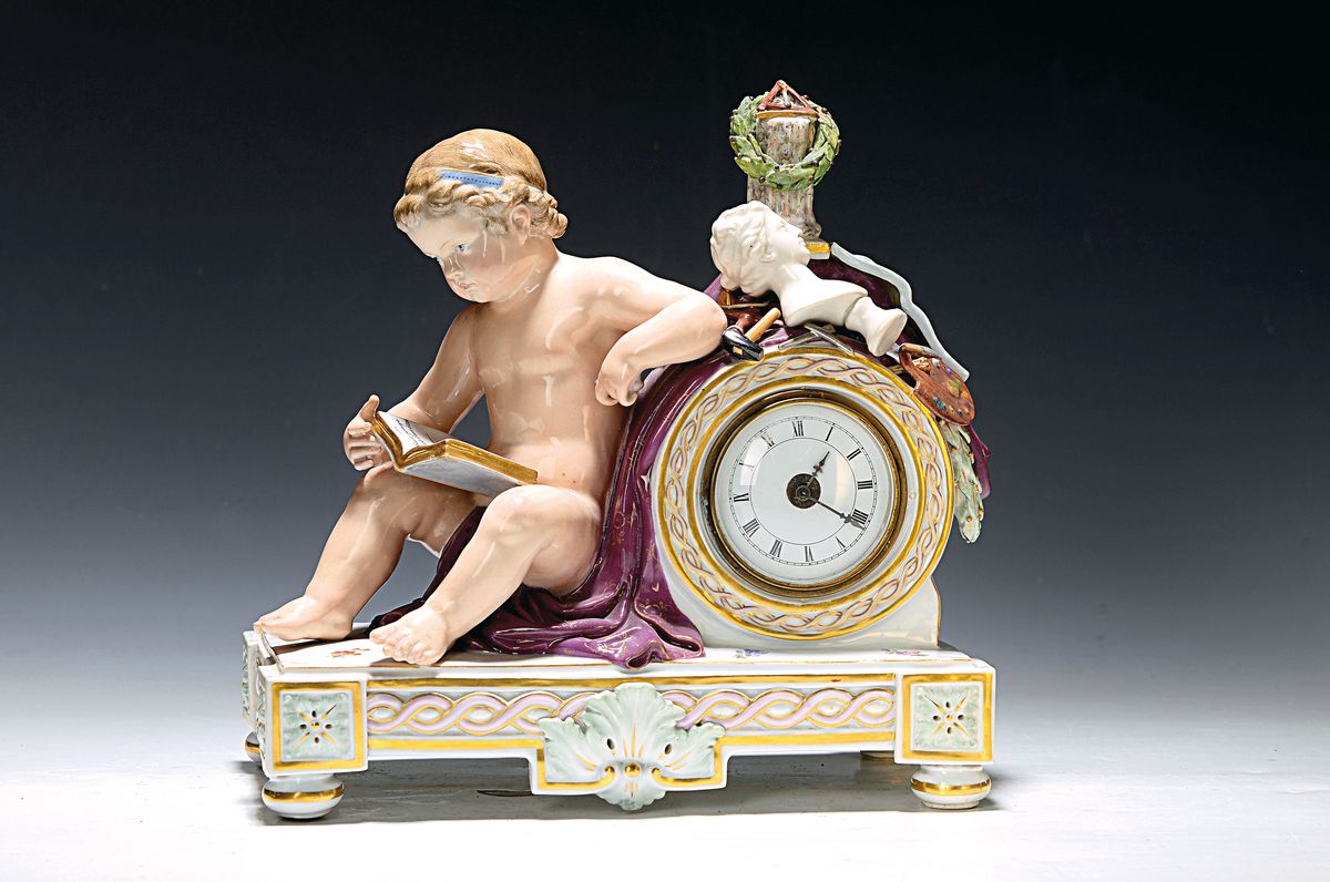 Tischuhr mit Figur, Meissen, 2. Hälfte 19. Jh., Porzellan, vollplastische Figur einer lesenden Amorette, auf der Uhr Büste, Malerpalette, Trompete ...