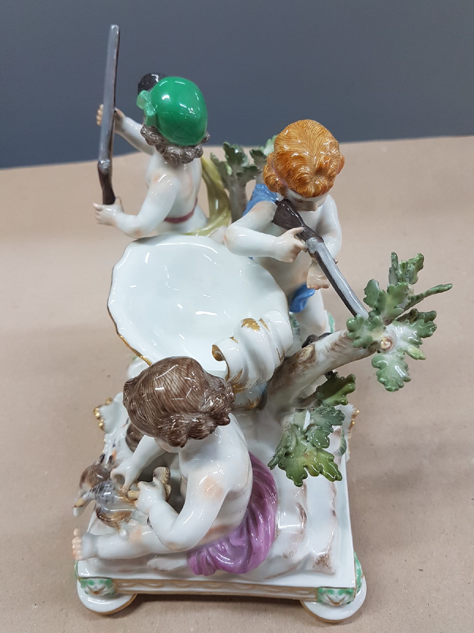 Detail b: Seltener Tafelaufsatz mit Putten, Meissen, um 1900, zentrale Muschelschale auf Felsen, umgeben von drei Putten mit jagdlichen Attributen: zwei mit ...