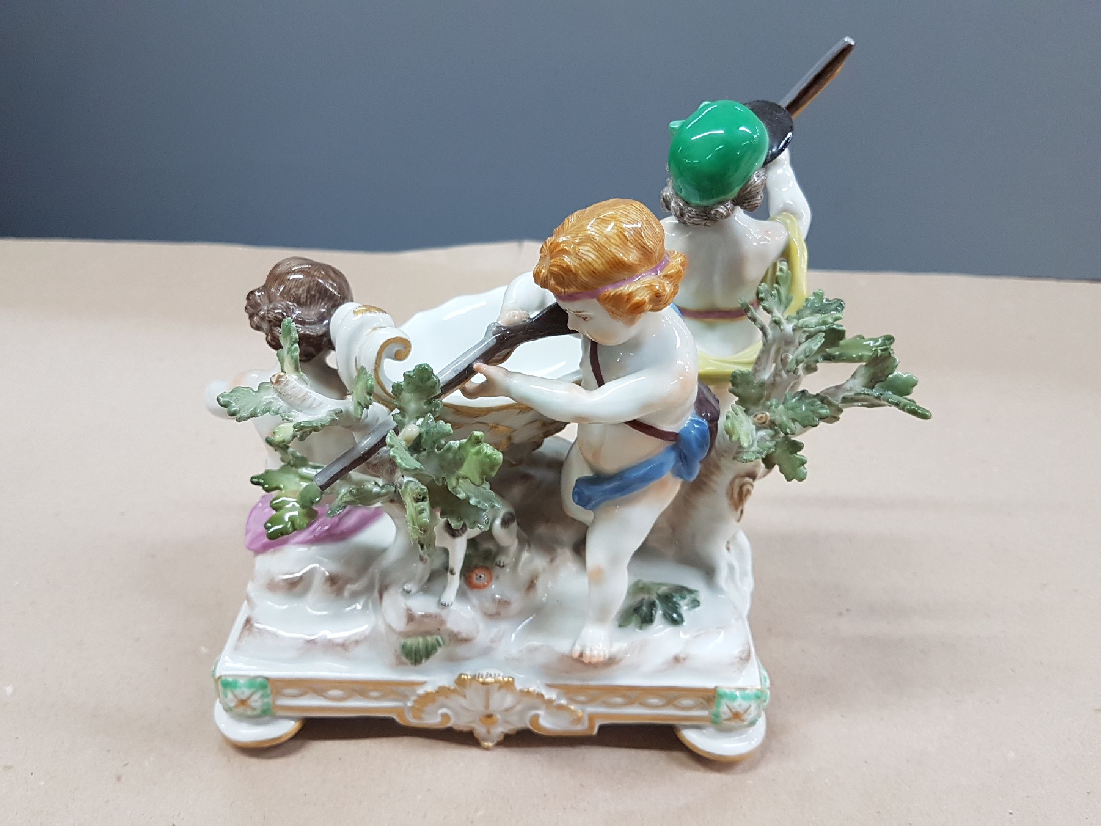 Detail c: Seltener Tafelaufsatz mit Putten, Meissen, um 1900, zentrale Muschelschale auf Felsen, umgeben von drei Putten mit jagdlichen Attributen: zwei mit ...