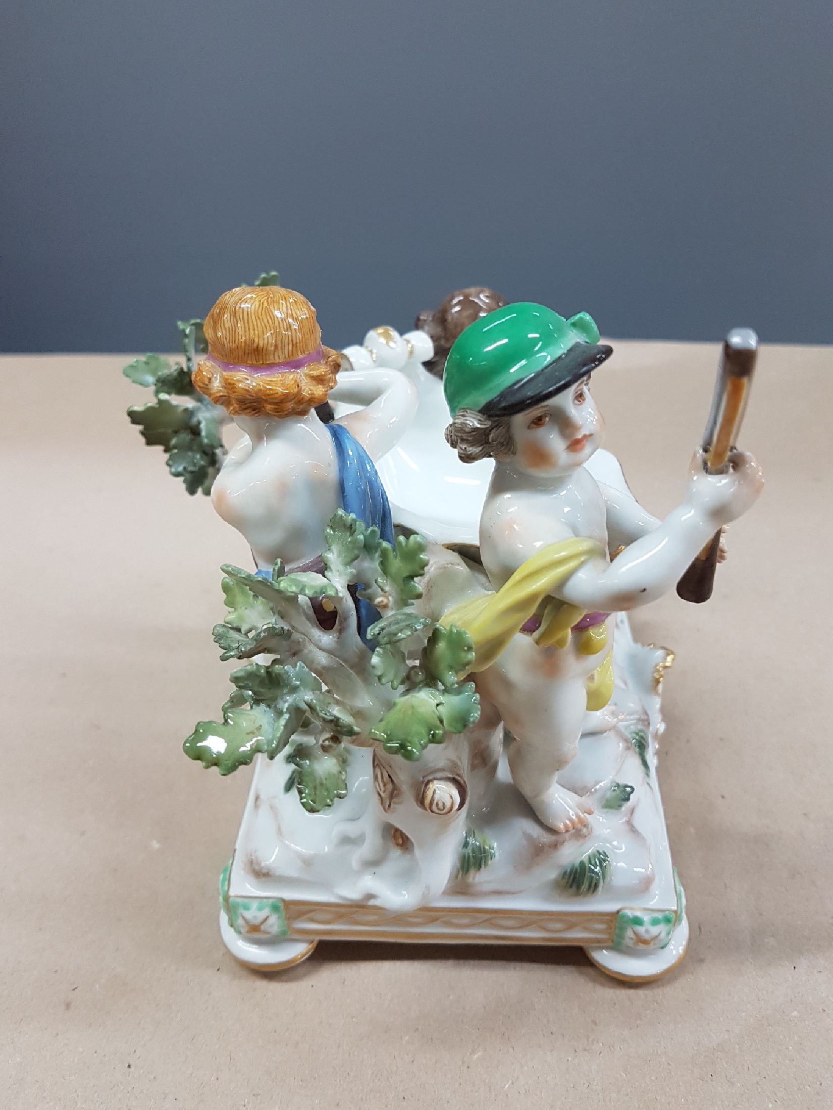 Detail d: Seltener Tafelaufsatz mit Putten, Meissen, um 1900, zentrale Muschelschale auf Felsen, umgeben von drei Putten mit jagdlichen Attributen: zwei mit ...
