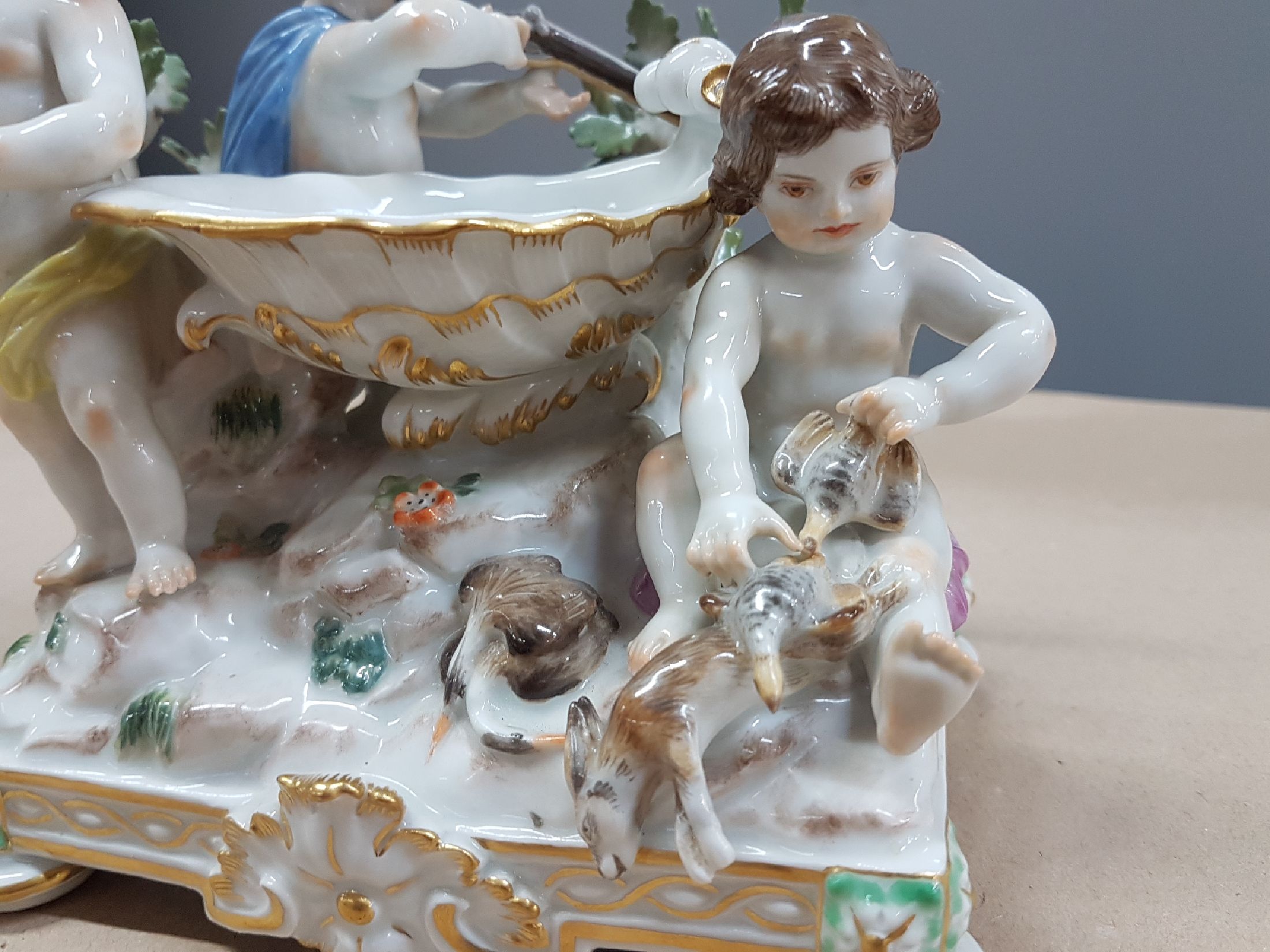 Detail f: Seltener Tafelaufsatz mit Putten, Meissen, um 1900, zentrale Muschelschale auf Felsen, umgeben von drei Putten mit jagdlichen Attributen: zwei mit ...