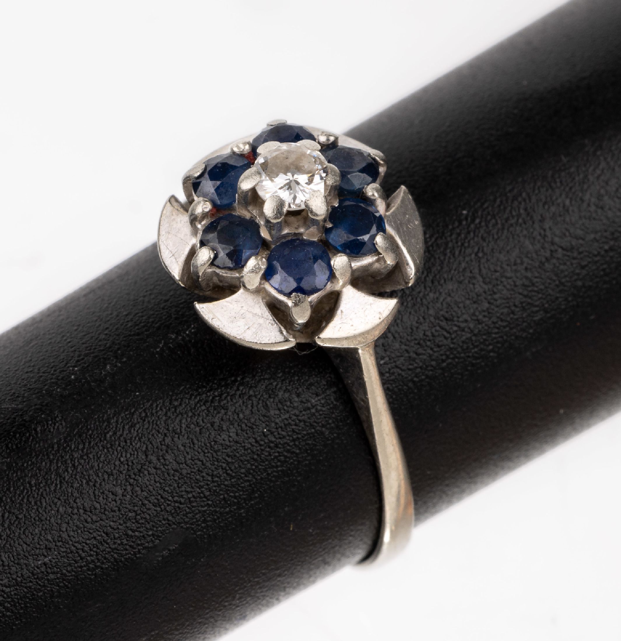 14 kt Gold Brillant-Saphir-Ring, WG 5585/000, mittig erhaben gefasster Brillant ca. 0.12 ct (grav.) Weiß/si, umgeben von 6 rundfacett. Saphiren ...