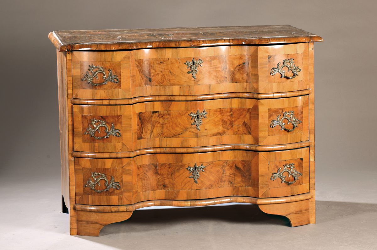Kommode, Barock, wohl Niedersachsen um 1760,Wurzelfurnier, z.T. Wurzelnuss, dreifach geschweift, drei Schubladen, Platte mit orig. Brandmalerei, ...