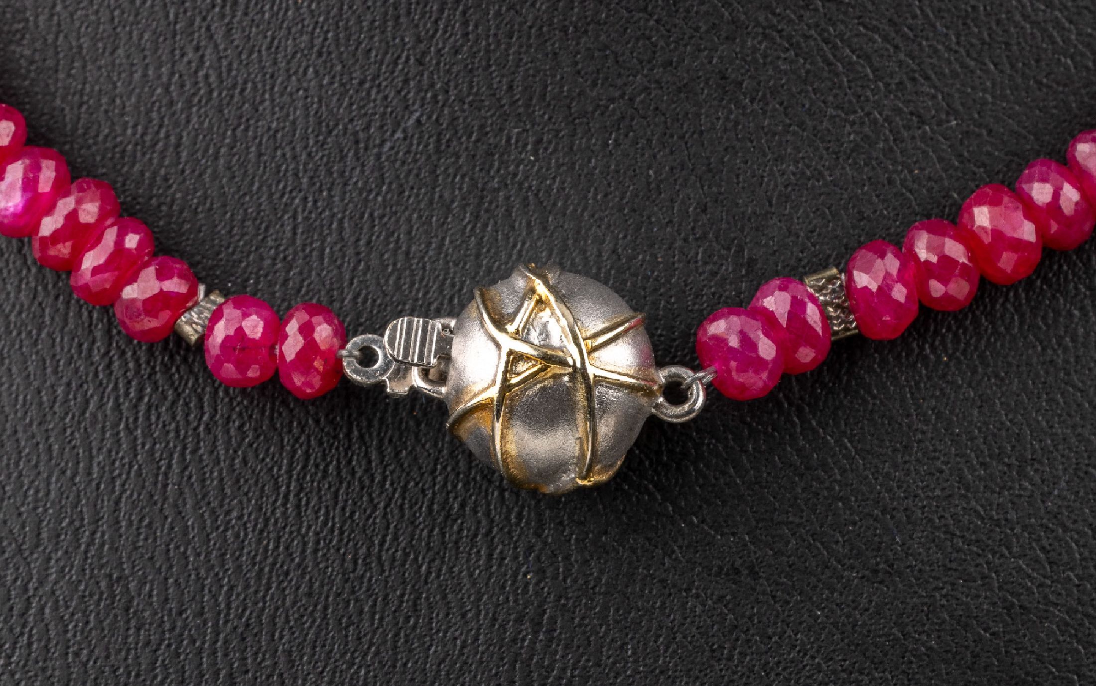 Detail a: Collier aus facett. Rubin-Rondellen mit 14 kt Gold Kugelschließe, GG/WG 585/000, facett. Rubin-Rondelle (beh.) zus. ca. 63.0 ct, L. ca.54 cm