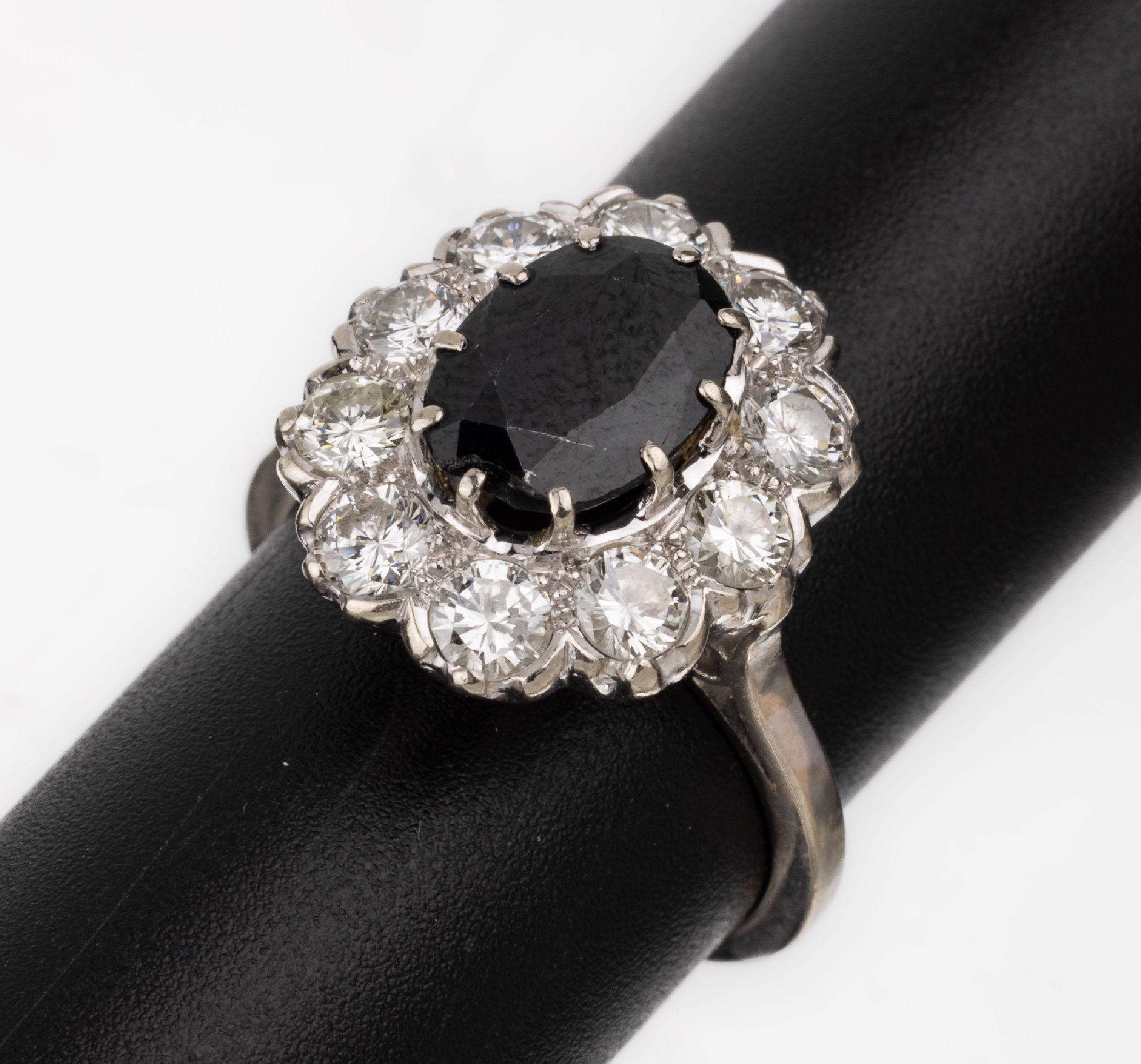 14 kt Gold Saphir-Brillant-Ring, WG 585/000, mittig ovalfacett. Saphir ca. 2.80 ct(besch.), umgeben von 10 Brillanten zus. ca. 1.50 ct ...