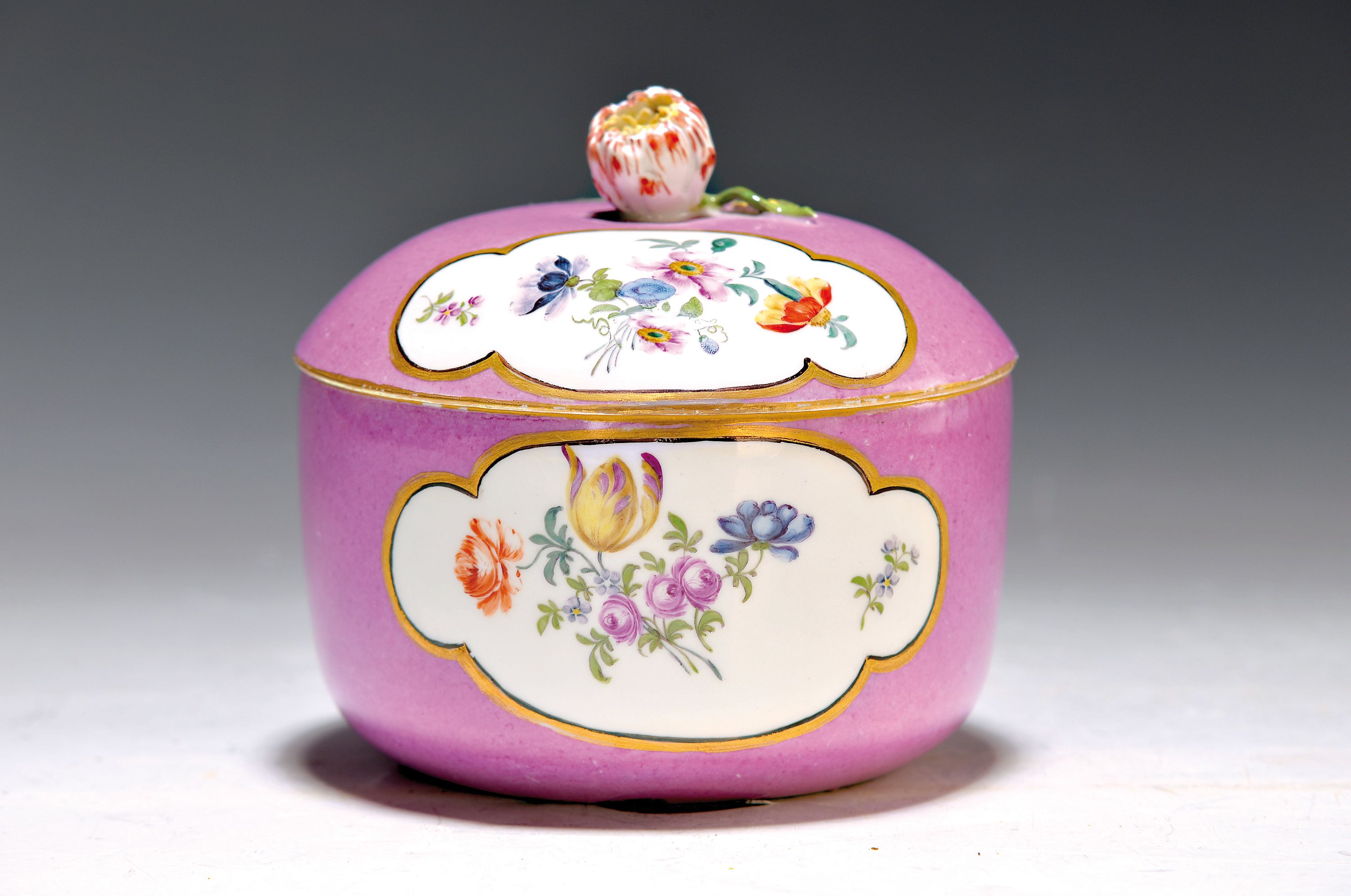 Deckeldose, Meissen, 18. Jh., violetter Fond, mit vier großen Gold und Schwarz gerahmten Reserven mit Blumenmalerei, Blumenbekrönung min. best., H. ...