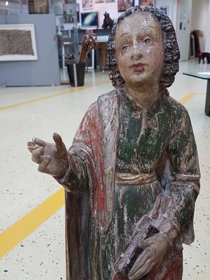 26725070e - Saint sculpture, southern German, 2nd half of the 18th century, carved wood, standing representation with book and gesture of instruction, remains of old version in green and red, curly hair, signs of age, 2 fingers missing, one present, height approx. 74cm
