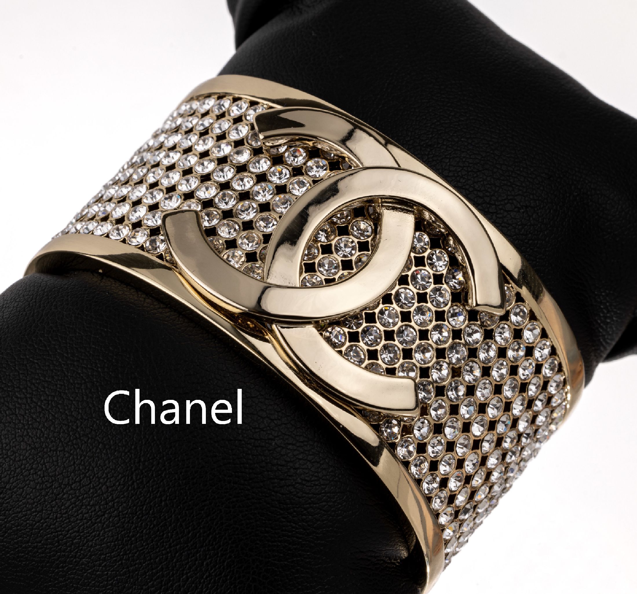 CHANEL Armreif, Metall verg., durchbrochen gearbeitet, aufgelegtes Chanel-Logo, Besatz mit farblosen Strasssteinen, ca. 6.2 x 3.2 cm,Öffnung 3 cm, ...