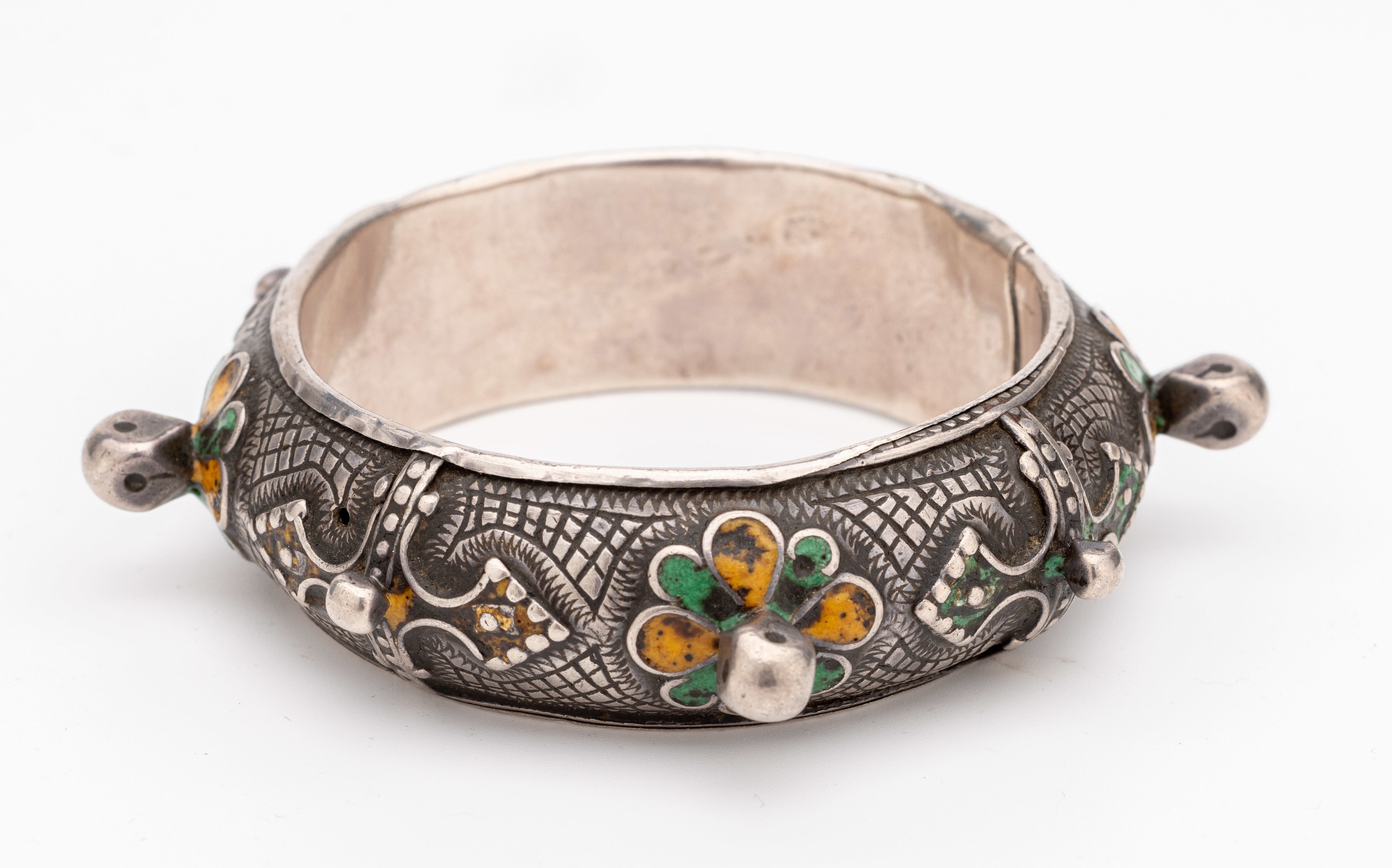 Detail a: Armreif mit Email, Silber gepr., wohl Marokko um 1900, oberfl. grav., Email in Grün und Gelb, D. ca. 5.9 cm, altersbed. Gebr. -Spuren