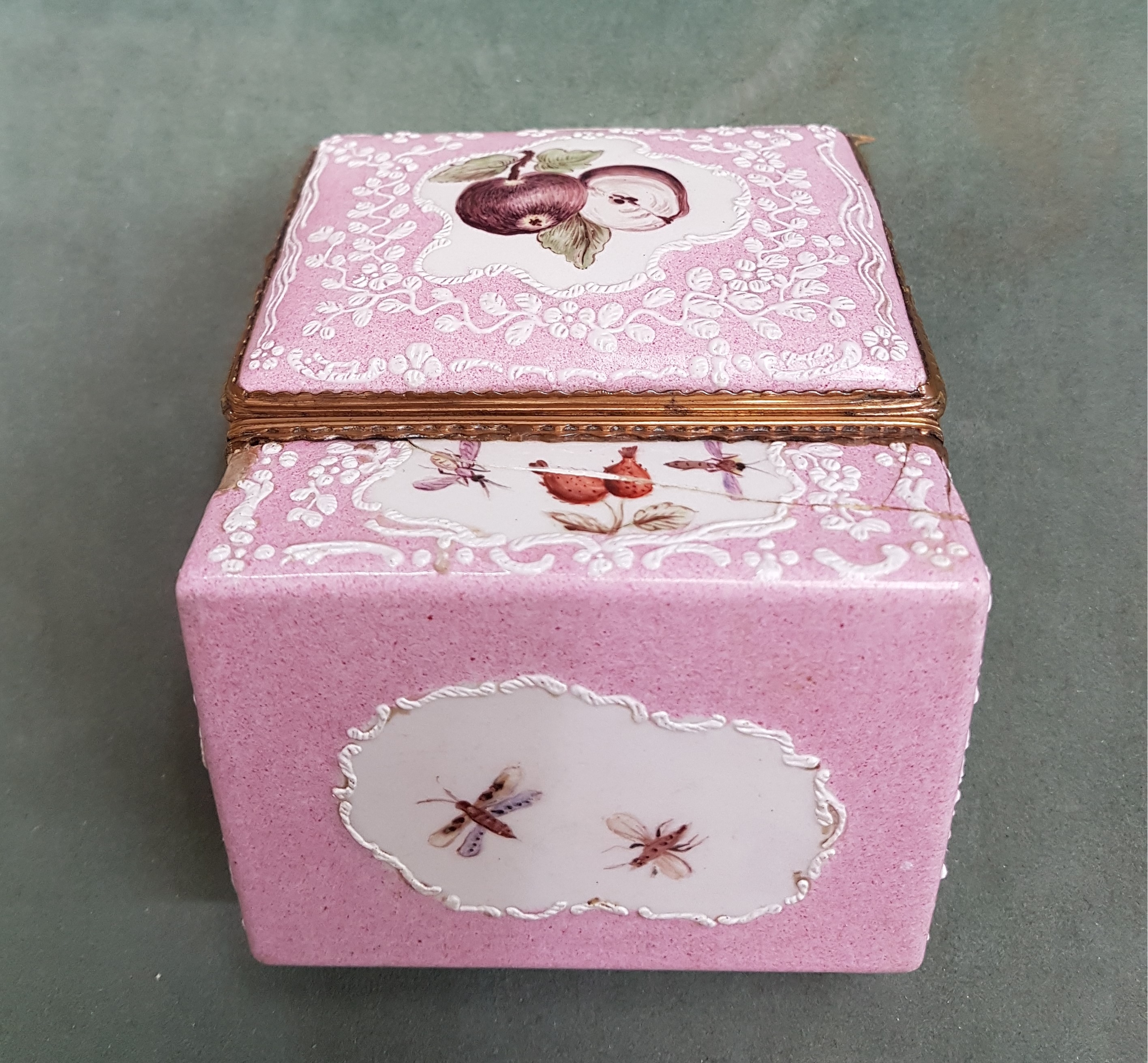 Detail h: Deckeldose, Frankreich, 19. Jh., Metall fein emailliert in rosa mit weißen aufgelegten Ornamenten, in Kartuschen Emailmalerei von Apfel, Pilzen, ...
