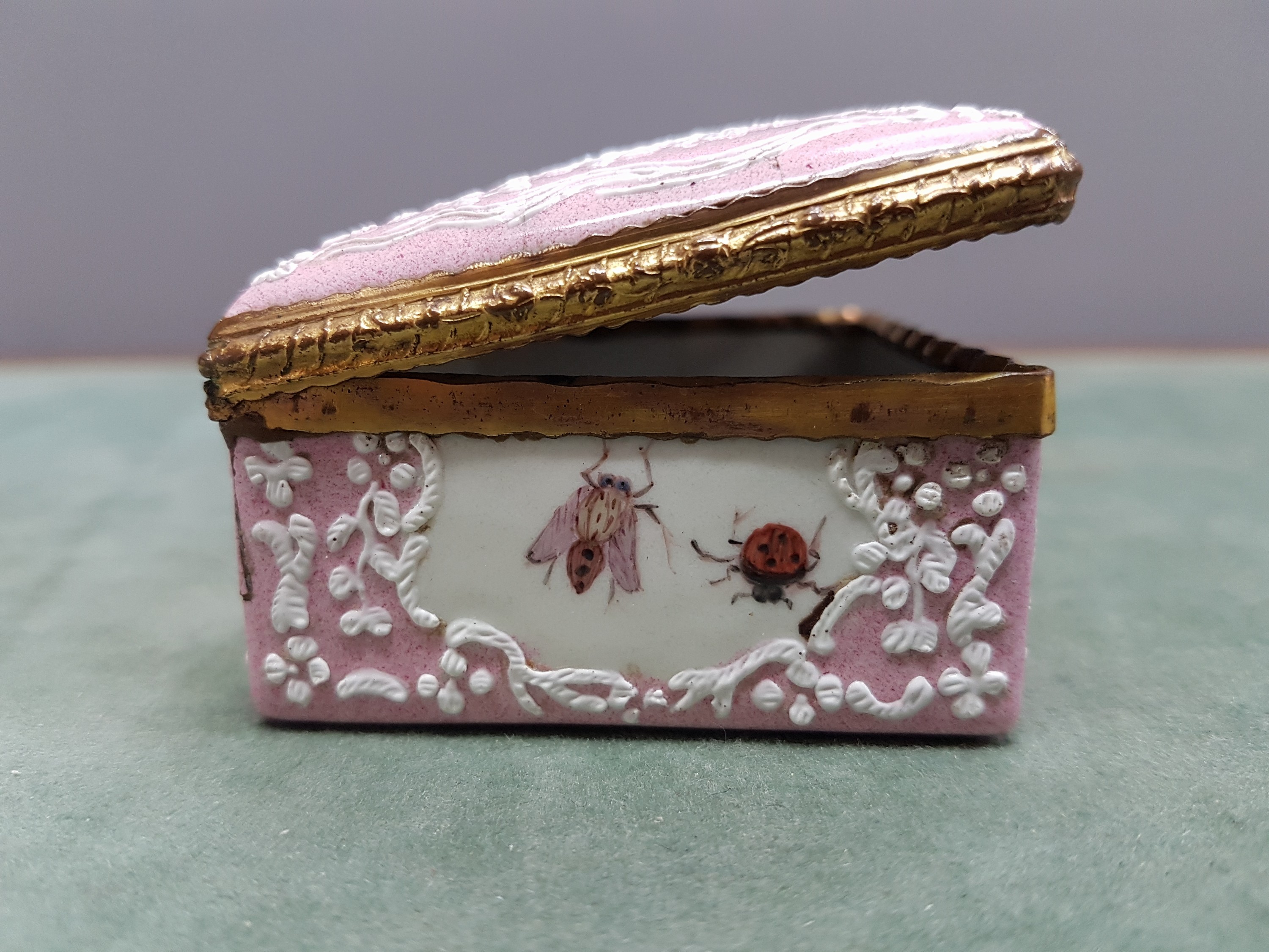 Detail j: Deckeldose, Frankreich, 19. Jh., Metall fein emailliert in rosa mit weißen aufgelegten Ornamenten, in Kartuschen Emailmalerei von Apfel, Pilzen, ...