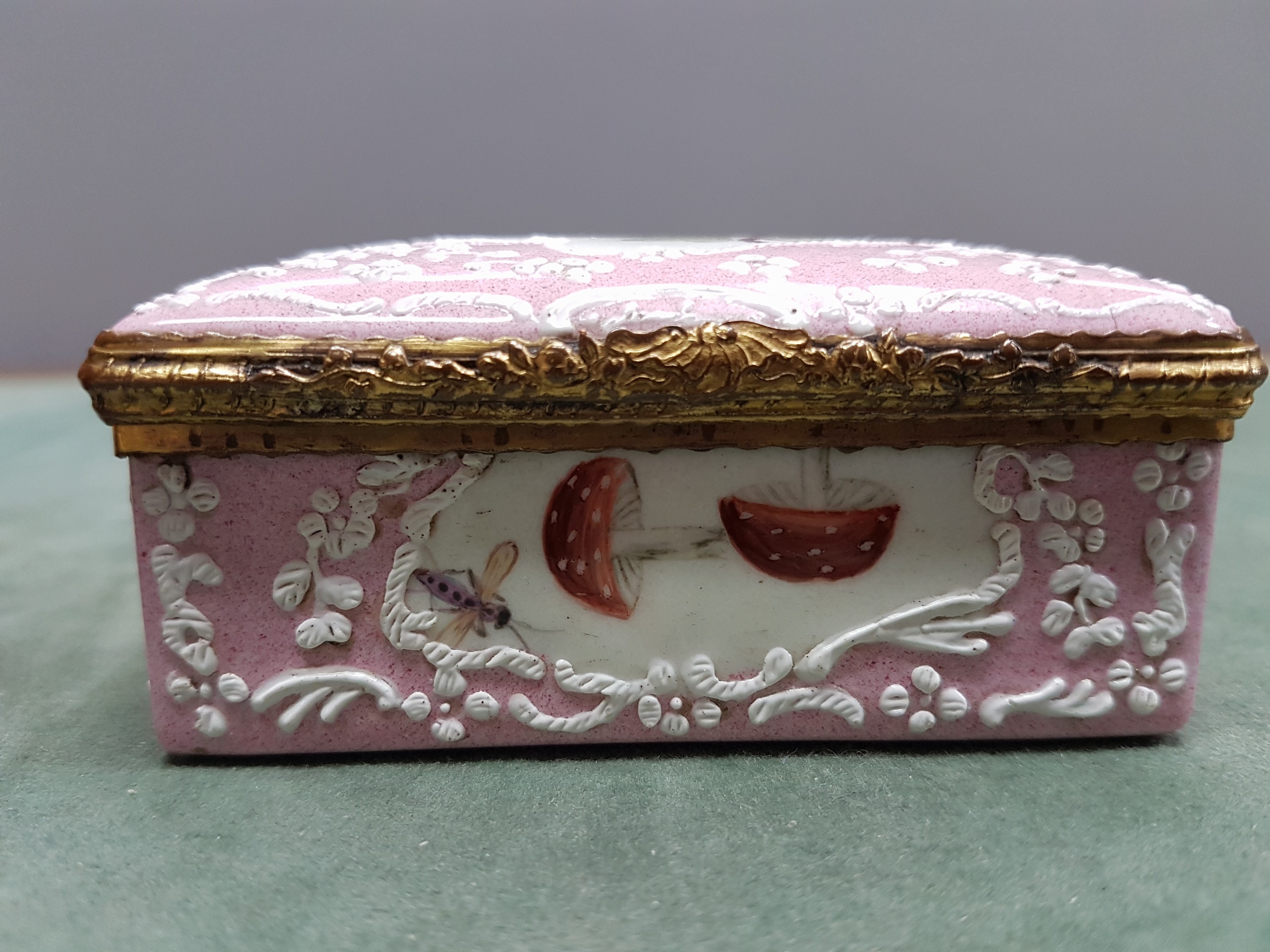 Detail k: Deckeldose, Frankreich, 19. Jh., Metall fein emailliert in rosa mit weißen aufgelegten Ornamenten, in Kartuschen Emailmalerei von Apfel, Pilzen, ...