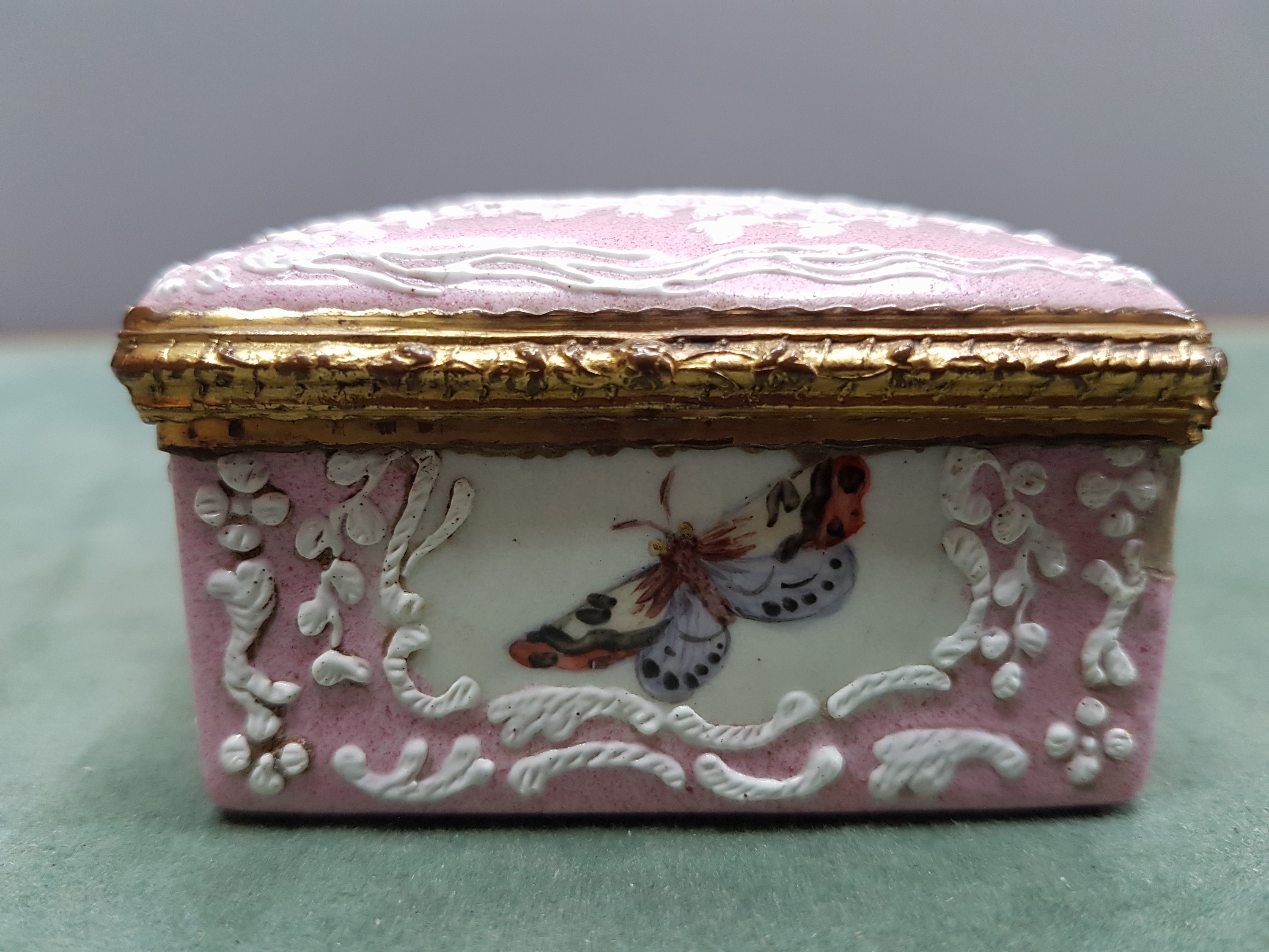 Detail l: Deckeldose, Frankreich, 19. Jh., Metall fein emailliert in rosa mit weißen aufgelegten Ornamenten, in Kartuschen Emailmalerei von Apfel, Pilzen, ...