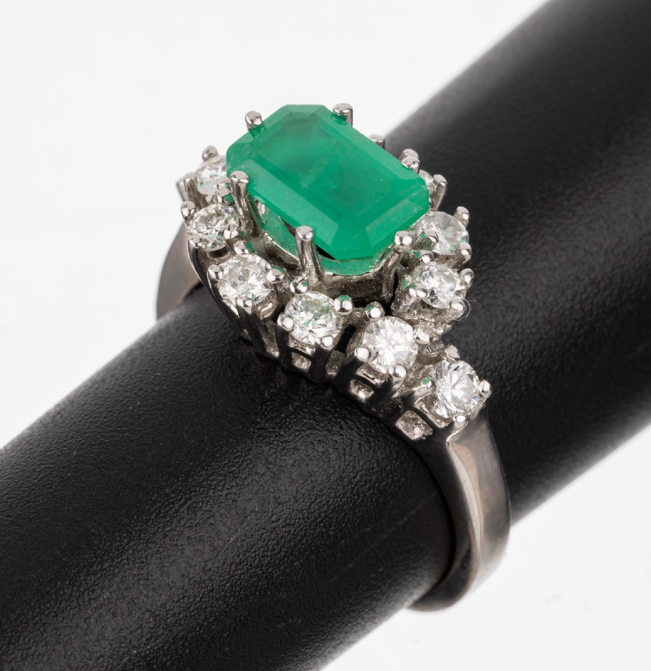 14 kt Gold Smaragd-Brillant-Ring, WG 585/000, mittig erhaben gefasster im Treppenschliff ca. 1.10 ct, umgeben von 12 Brillanten zus. ca. 0.64 ct ...