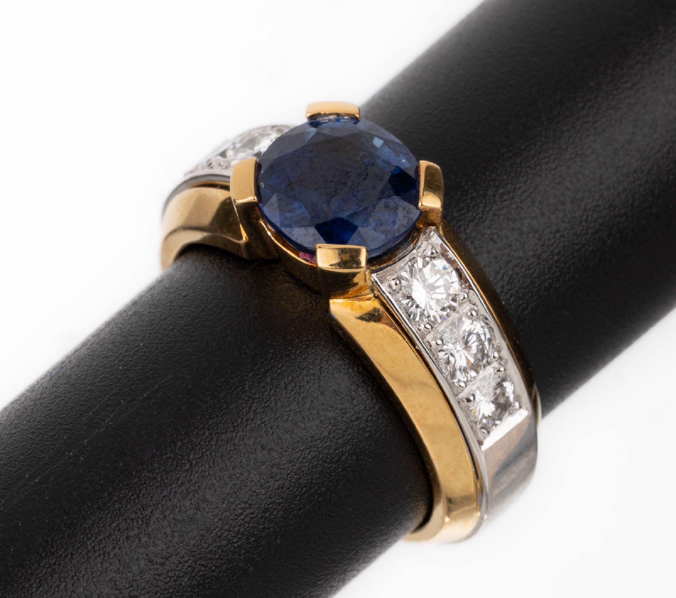 18 kt Gold Saphir-Brillant-Ring, GG/WG 750/000, mittig ovalfacett. Saphir von schönerFarbe ca. 2.61 ct, seitl. 6 Brillanten zus. ca. 0.63 ct feines ...