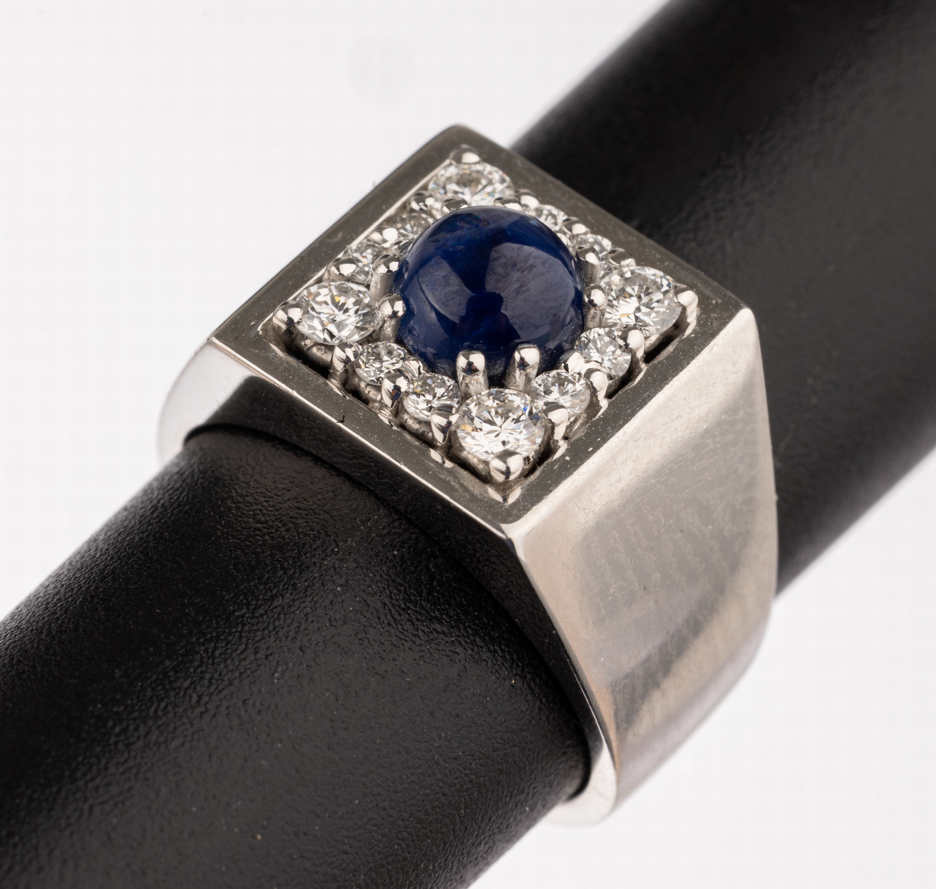 18 kt Gold Saphir-Brillant-Ring, WG 750/000, Ringkopf quadratisch, mittig runder Saphir-Cabochon ca. 1.03 ct, 12 Brillanten zus. ca. 0.36 ct ...