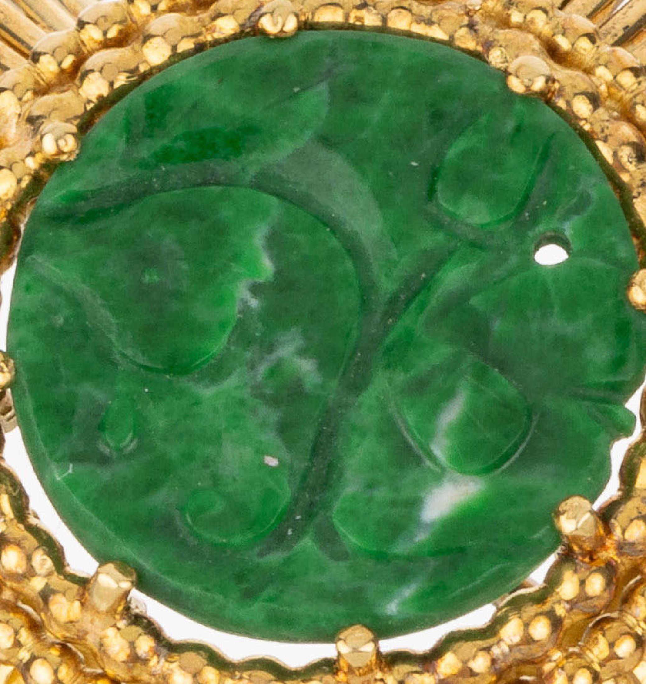 Detail a: 18 kt Gold Jade-Brosche, GG 750/000, Goldstäbe wellenförmig, mittig Jadeeinlage mitBlütengravur (gebohrt), Perlleistenverzierung,ca. 10.1 g, D. ...