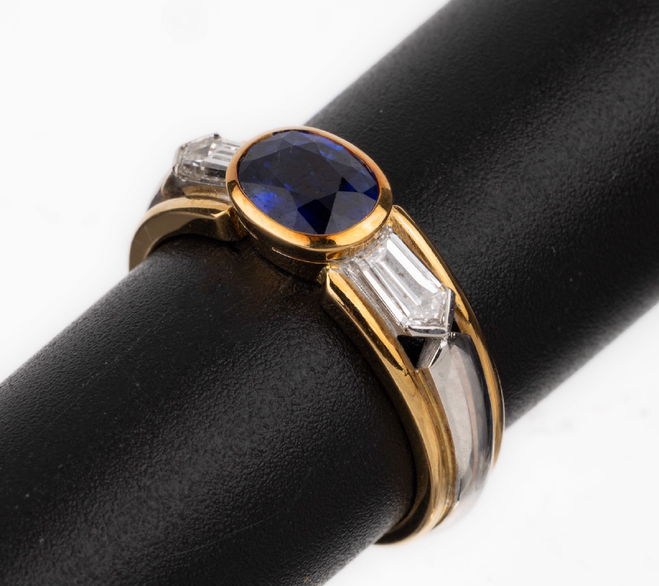 18 kt Gold Saphir-Diamant-Ring, GG/WG 750/000, ovalfacett. Saphir von intensiver Farbe ca. 1.34 ct, 2 Diamanten im Phantasieschliff zus. ca. 0.47 ct ...