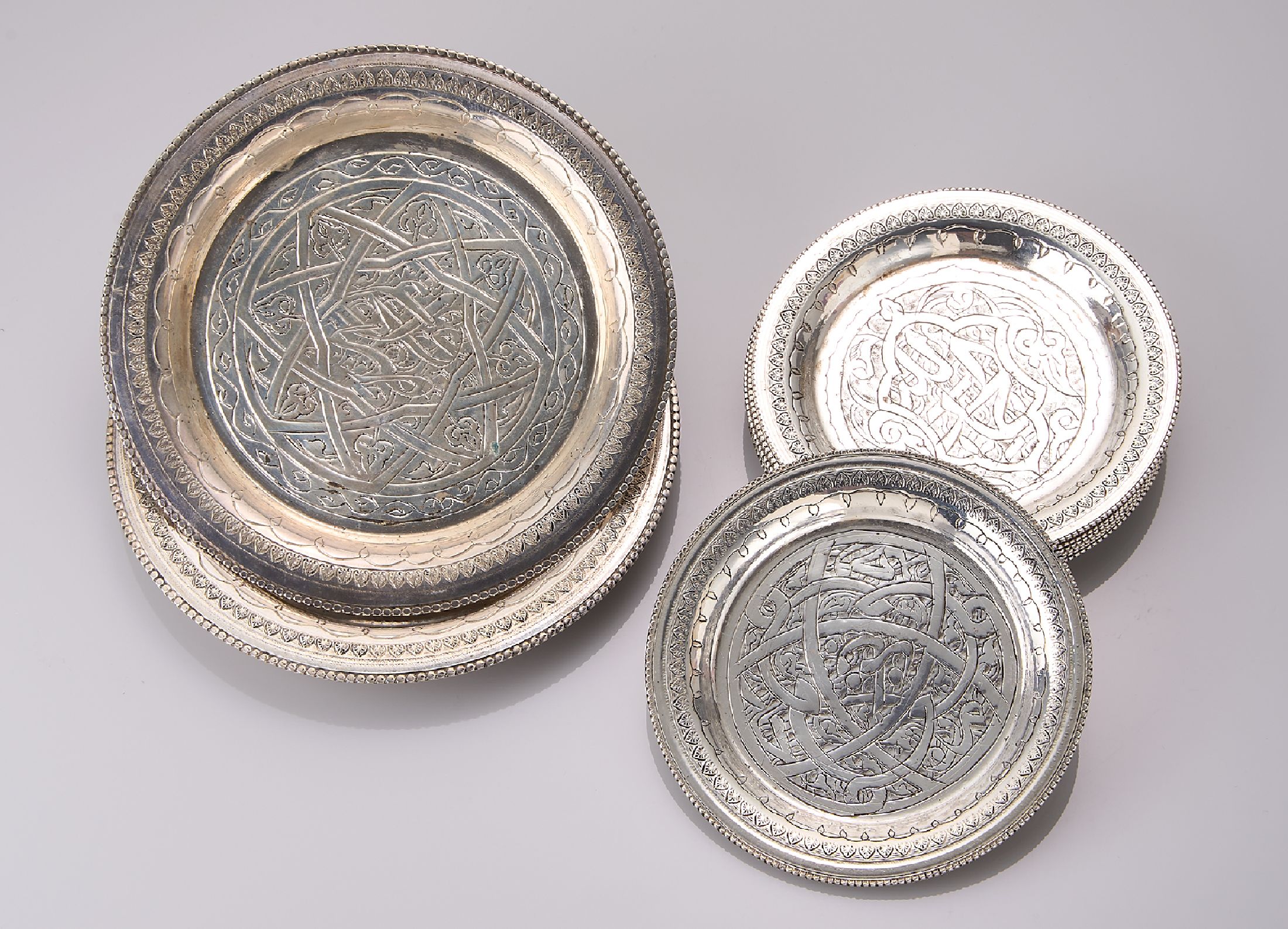 Set 12 Untersetzer, Silber gepr., wohl Ägypten um 1950, reich graviert, 2 x D. ca. 11.8 cm, 10 x D. ca. 8.9 cm, ca. 440 g